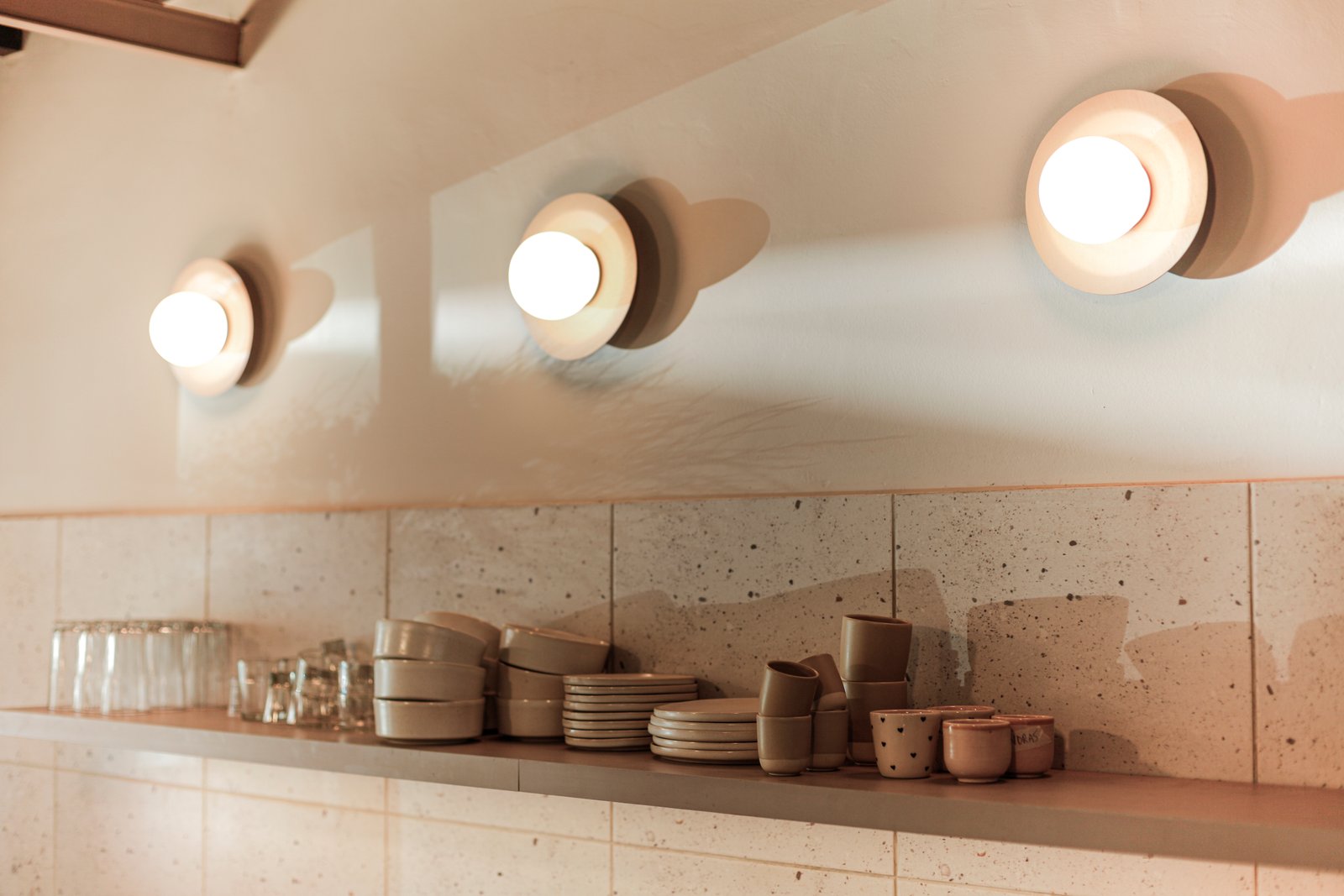 Cocina minimalista con luces de pared texturizadas y almacenamiento integrado — proyecto La Selva Yoga - Cafe, por Jeitinho Estudió Creativo, en La Plata