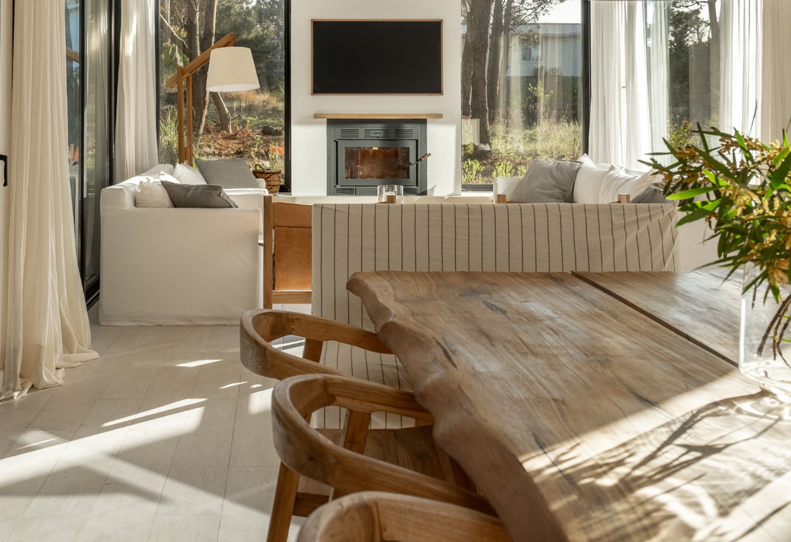 Living comedor moderno con chimenea y ventanales al bosque — proyecto PROYECTO LA NEGRA DE CASA ORILLA, por ILVA, en Provincia de Buenos Aires