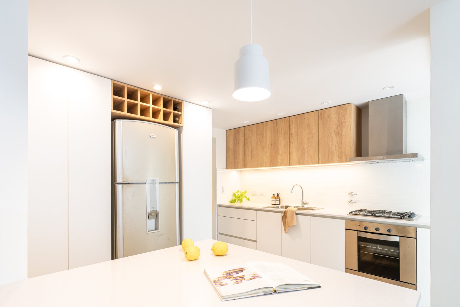 Cocina moderna con heladera acero inoxidable y muebles madera y blancos — proyecto SANTA FE, por Maria Menna Arquitecta, en Mar del Plata