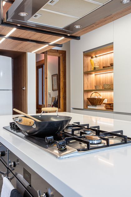 Cocina moderna con isla, anafe integrado y muebles de madera — proyecto Casa Nordelta, por Gutman+Lehrer Arquitectas, en Nordelta