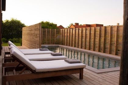 Pileta con deck y reposeras frente a pergola de madera — proyecto JI 103, por Estudio Diez Muzzio