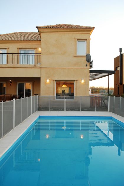 Pileta rectangular con cerco de seguridad y casa contemporánea al fondo — proyecto Proyectos 200 m2, por Ciba Arquitectura