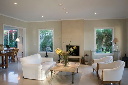 Living contemporáneo con sillones blancos y grandes ventanales hacia jardín — proyecto Racionalismo Moderno, por Ciba Arquitectura