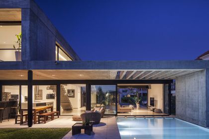 Moderna casa de hormigón con piscina y deck de madera de noche — proyecto CASA EH, por GMARQ