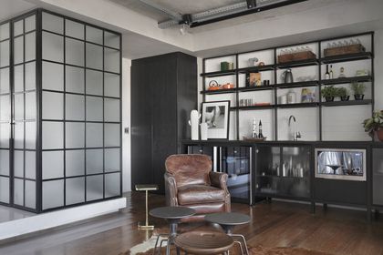 Oficina moderna con estantería negra, sillón cuero y ventanal industrial — proyecto RA Loft, por Studio Ro-ca