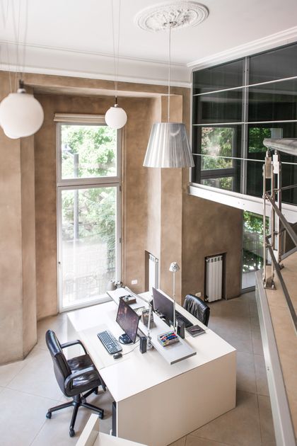 Oficina moderna doble altura con escritorio blanco y ventanal arbolado — proyecto Estudio Cerviño, por Estudio Du , en Palermo