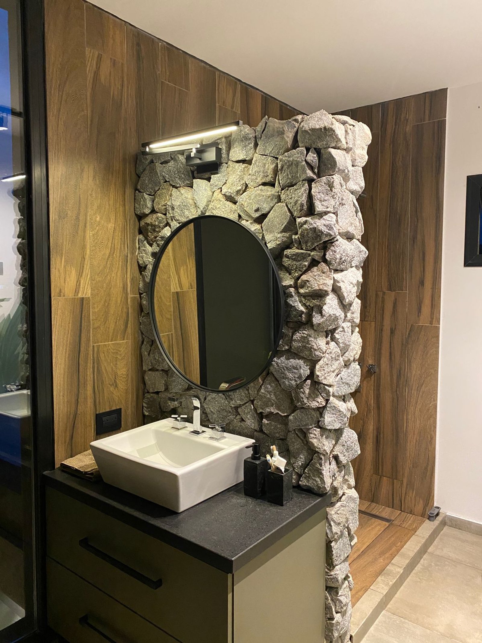 baño moderno con pared de piedra y madera — proyecto Casa Tulum, por vetainteriores, en Pergamino