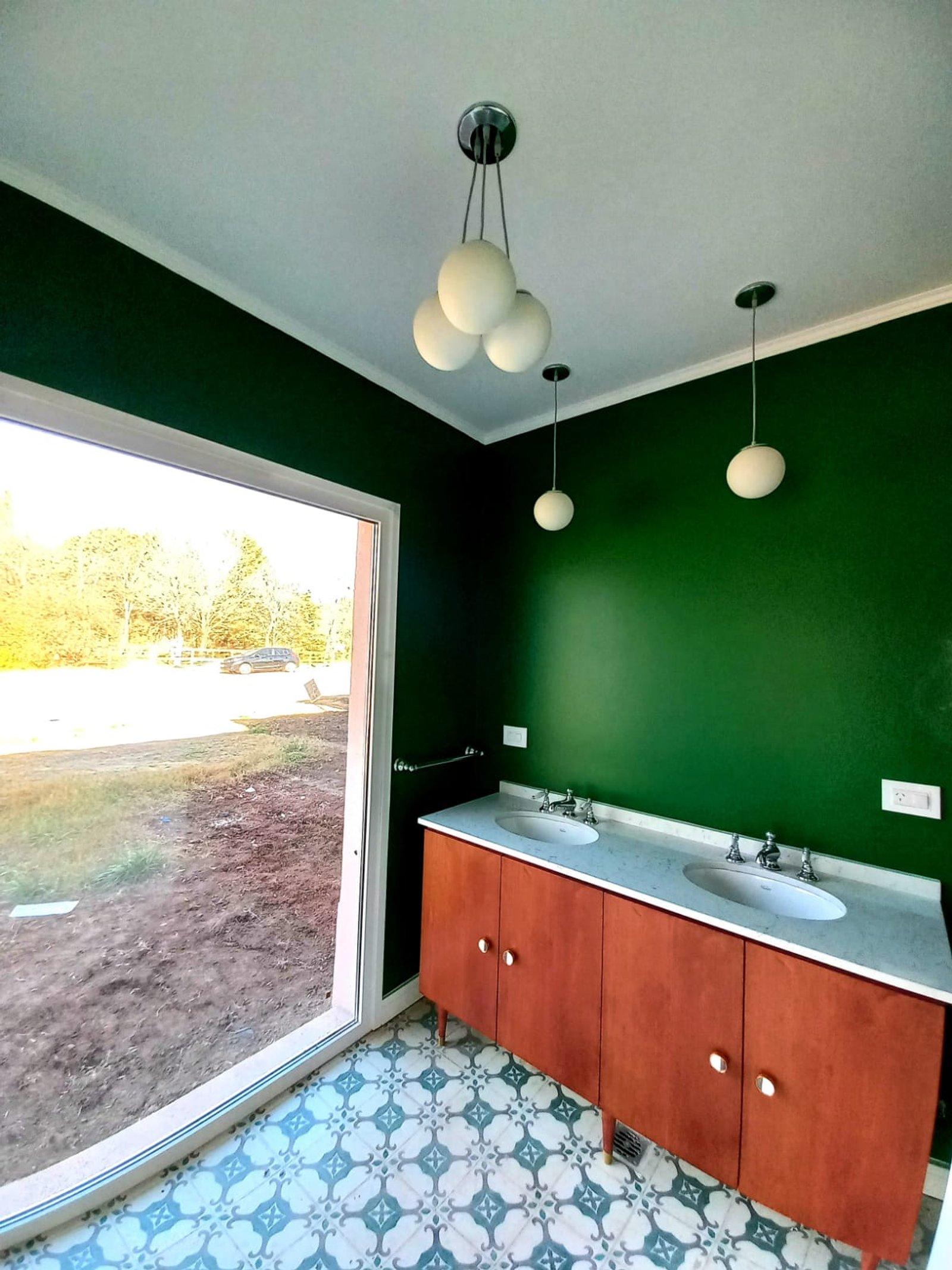 Baño con grandes ventanales, mueble de madera y luces colgantes — proyecto Casa de Campo, por Estudio Fernandez Long & asoc., en San Andres de Giles