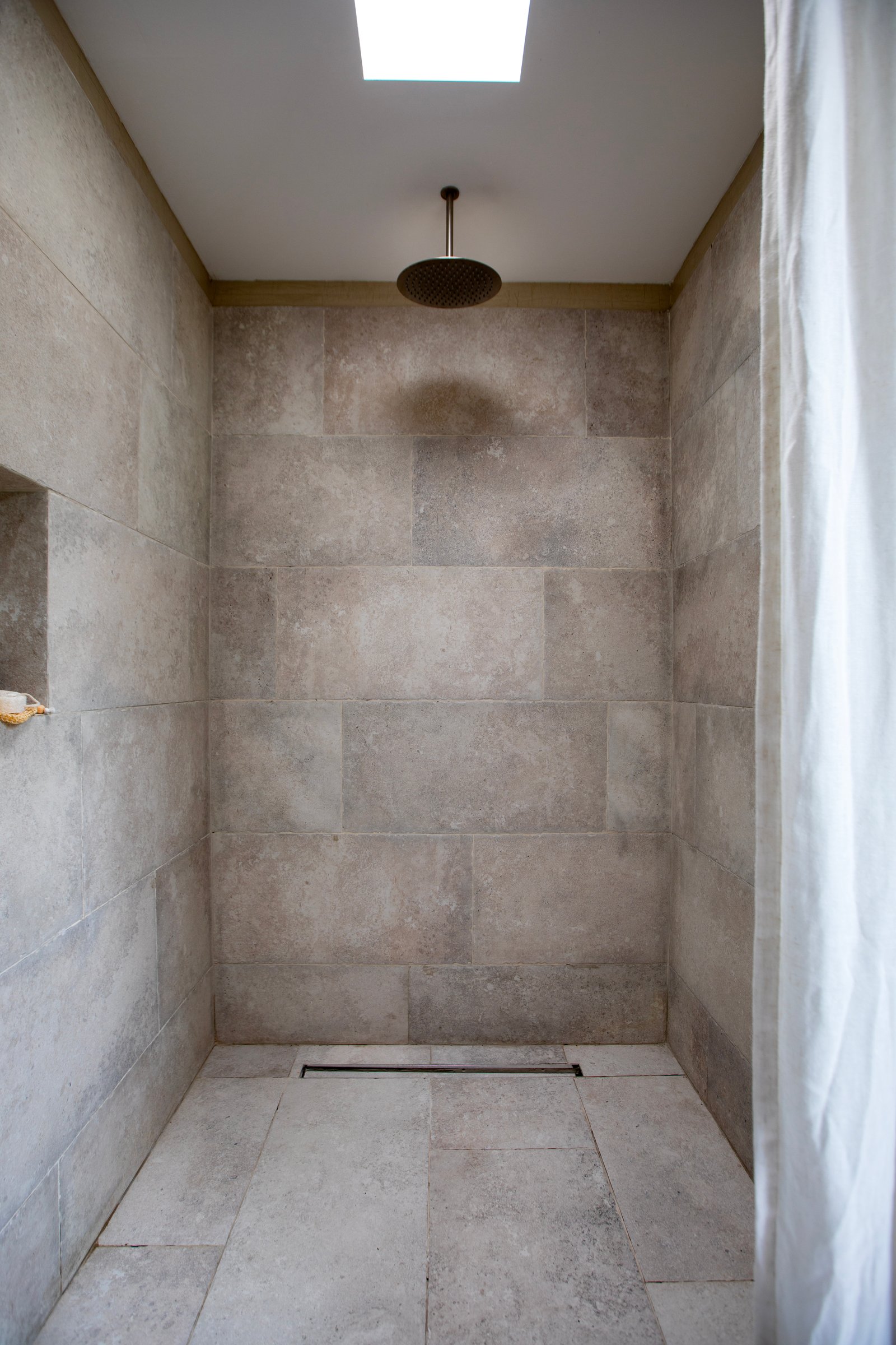ducha moderna con azulejos de piedra y tragaluz — proyecto OBRA EL DESCANSO, por ILVA, en Provincia de Buenos Aires