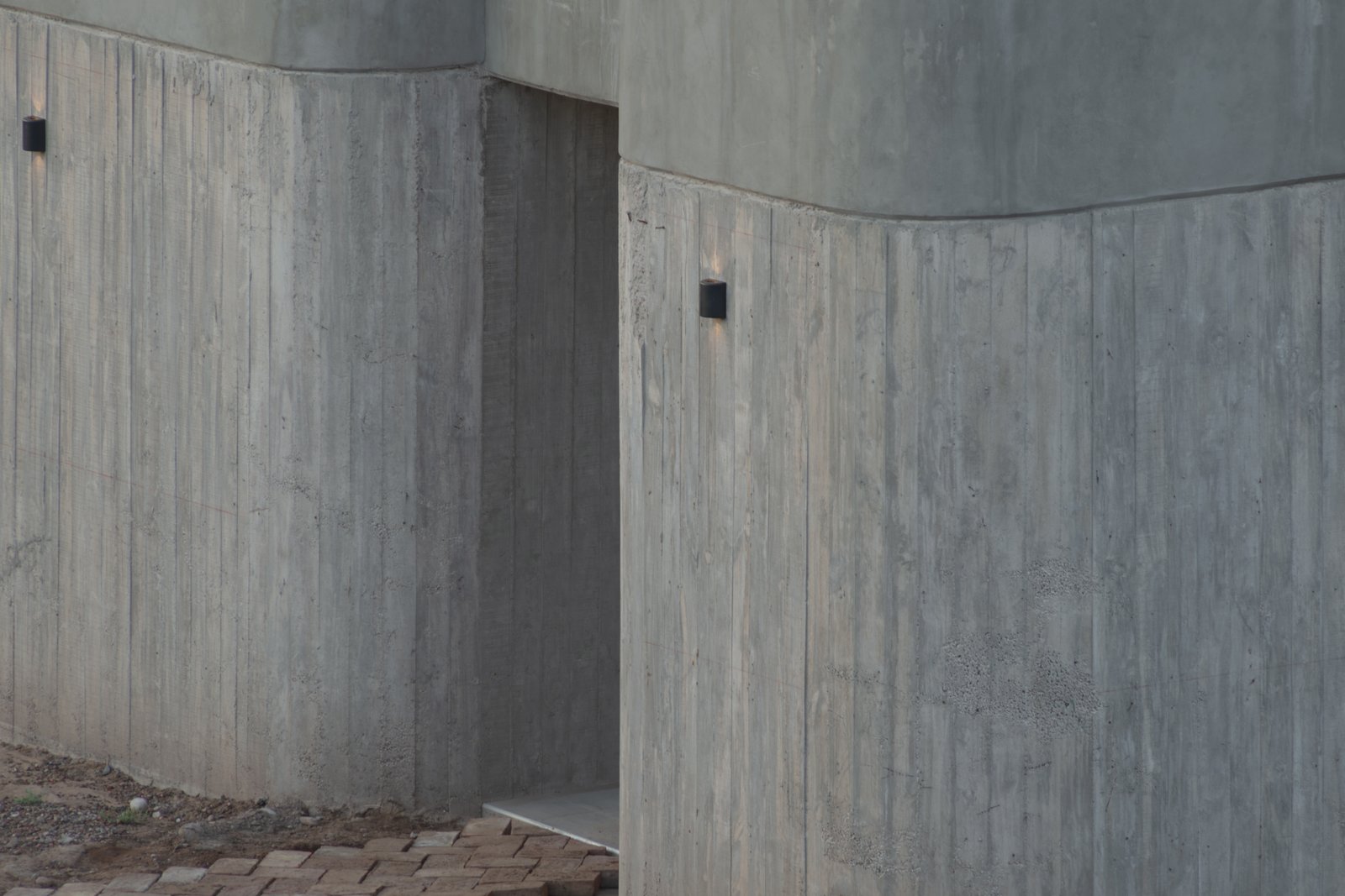 fachada moderna de concreto com paredes curvas — projeto Complejo SCV, por ONA - Oficina Nómada de Arquitectura, em Las Compuertas