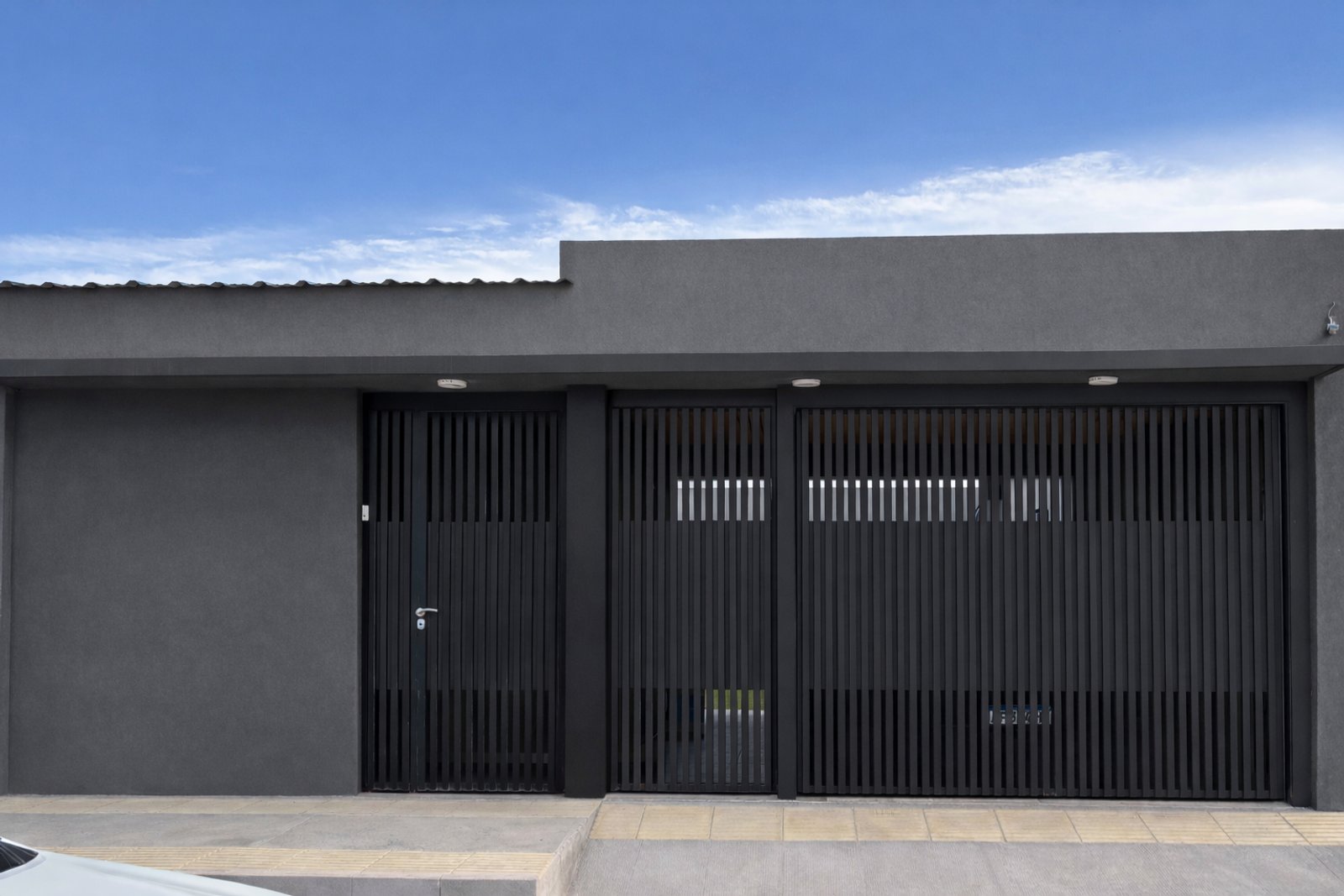 fachada moderna cinza com portão preto vertical — projeto Casa AJ, por Pedro Vilchez, em Neuquén