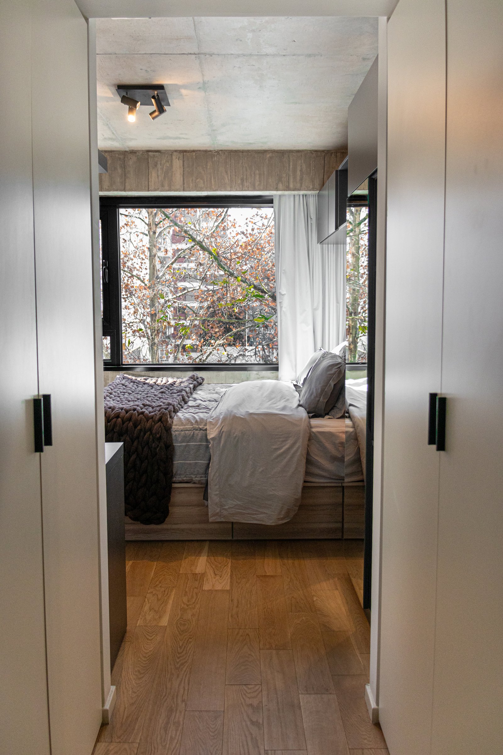 Dormitorio con vista angosta, piso de madera y techo de hormigón — proyecto Guatemala , por KUPERDESIGN CONSTRUCCIONES SRL, en Palermo