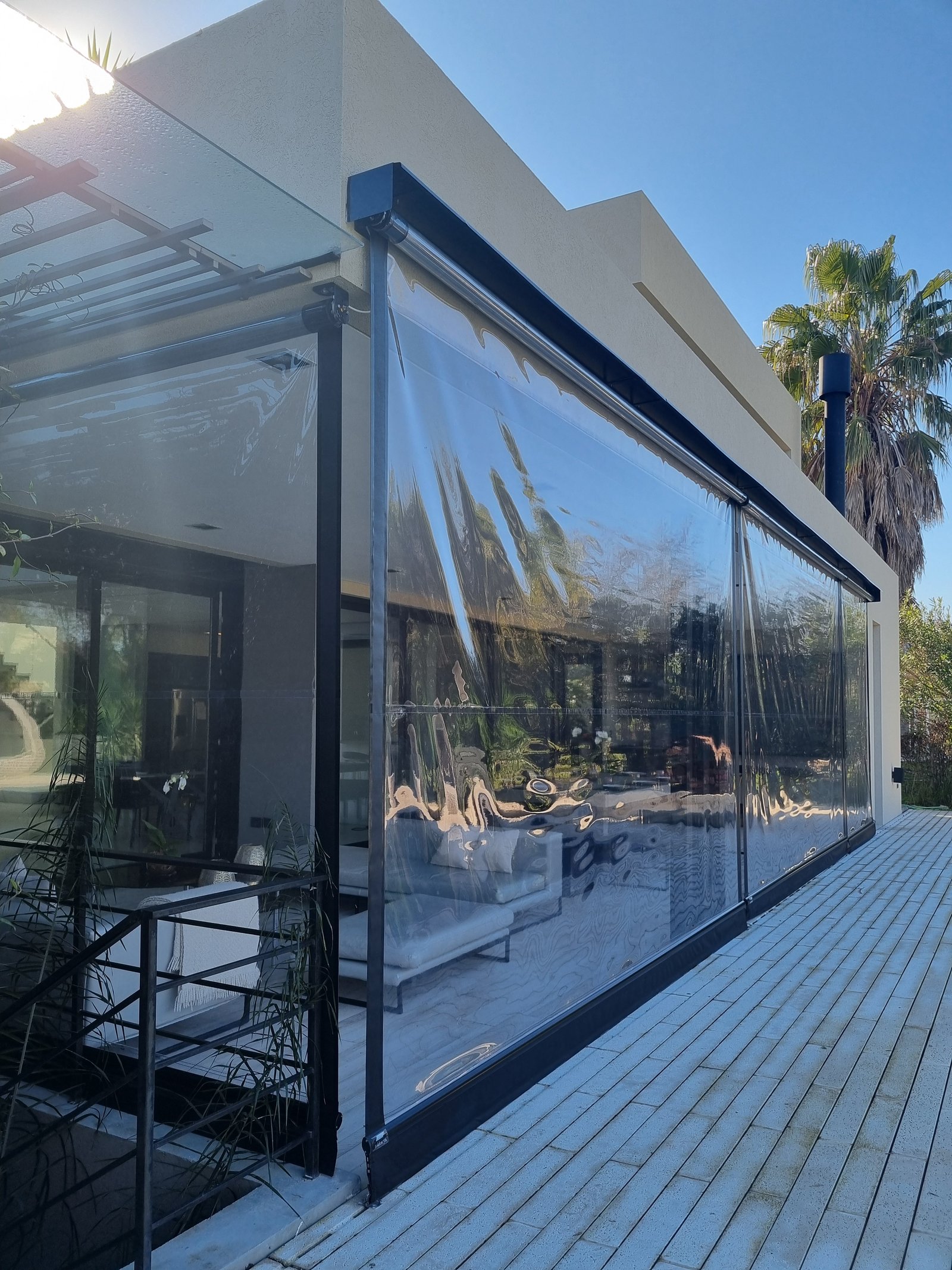 Terraço moderno com cortinas transparentes e deck de madeira — projeto Toldos Verticales, por ToldosYa