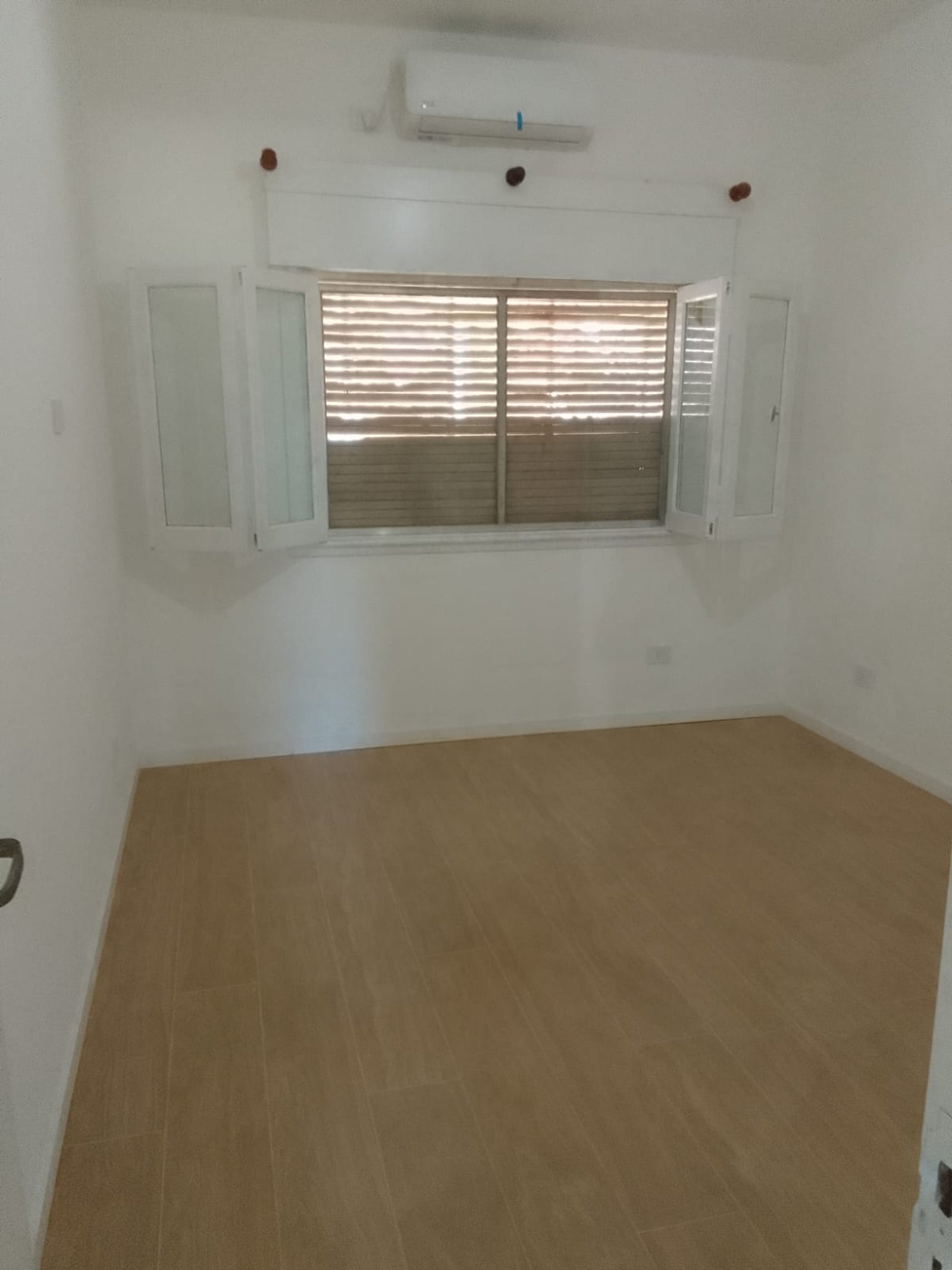 Dormitorio vacío con pisos de cerámica beige y ventana grande — proyecto Casa en Banfield, por Arquitecto Guido Niccoli, en B1828 Banfield