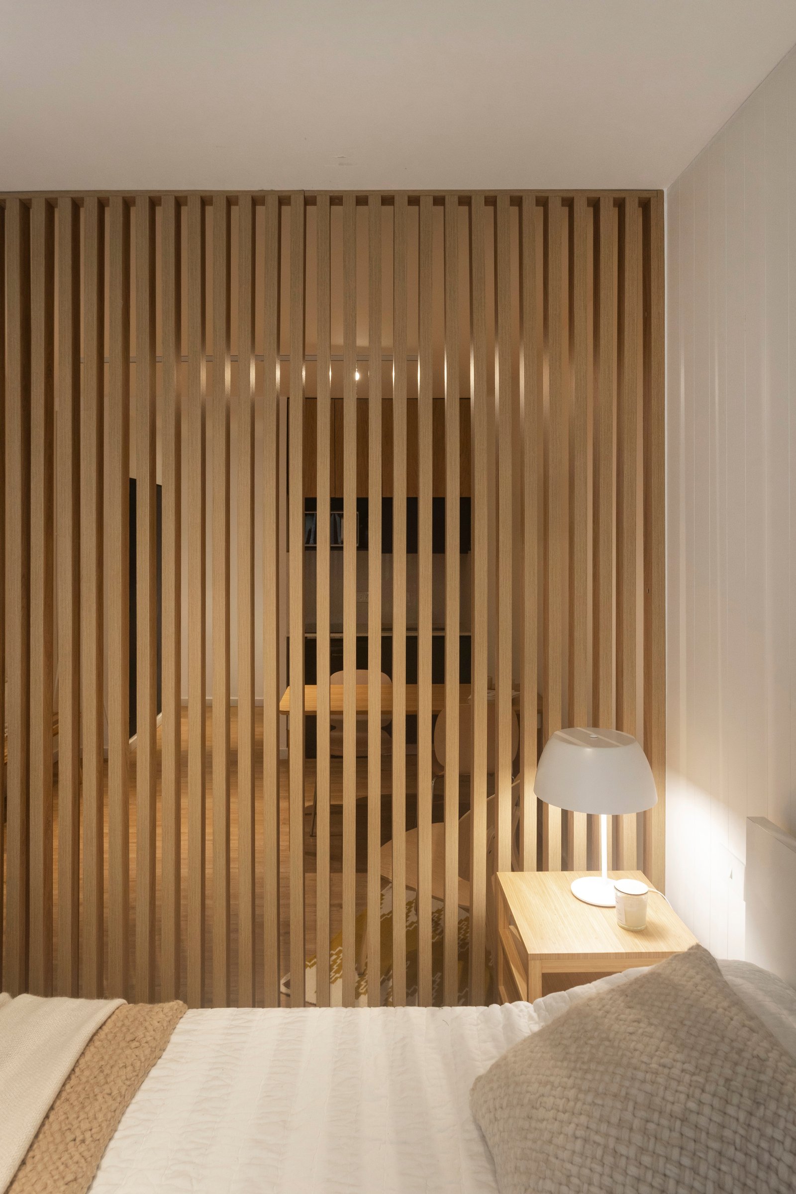 Quarto moderno com divisória de ripas de madeira e cama branca — projeto REFORMA NE, por Rastro Estudio, em Palermo