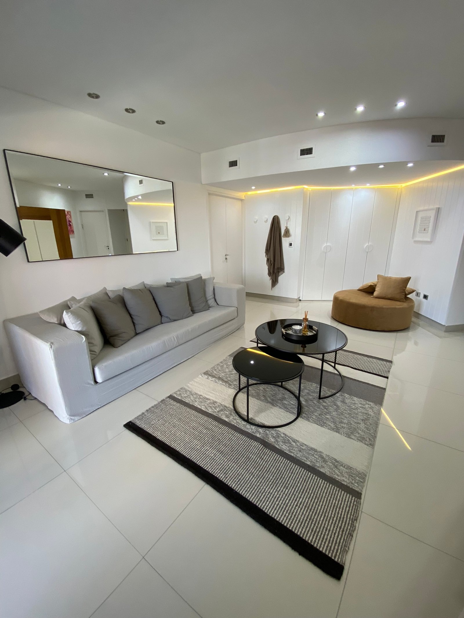 Living moderno con sofá modular gris y mesas de café redondas — proyecto Juncal II, por MDBK Arquitectura, en Palermo