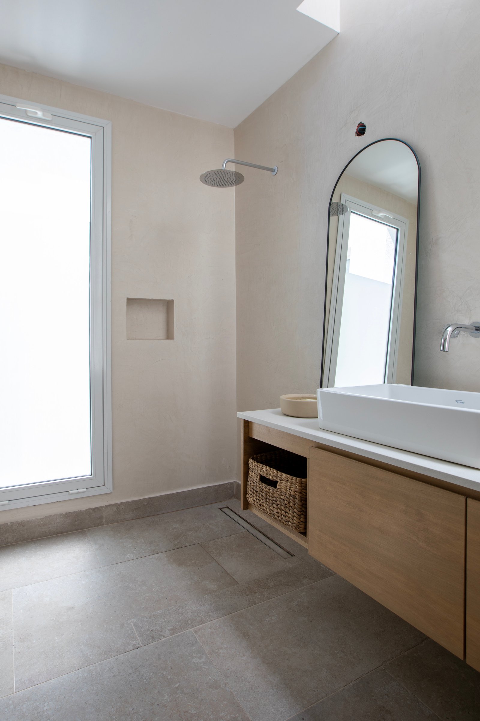 Baño moderno minimalista con ventana grande y espejo arqueado — proyecto OBRA LE PIETRE DEL CASALE SABBIA, por ILVA, en Provincia de Buenos Aires