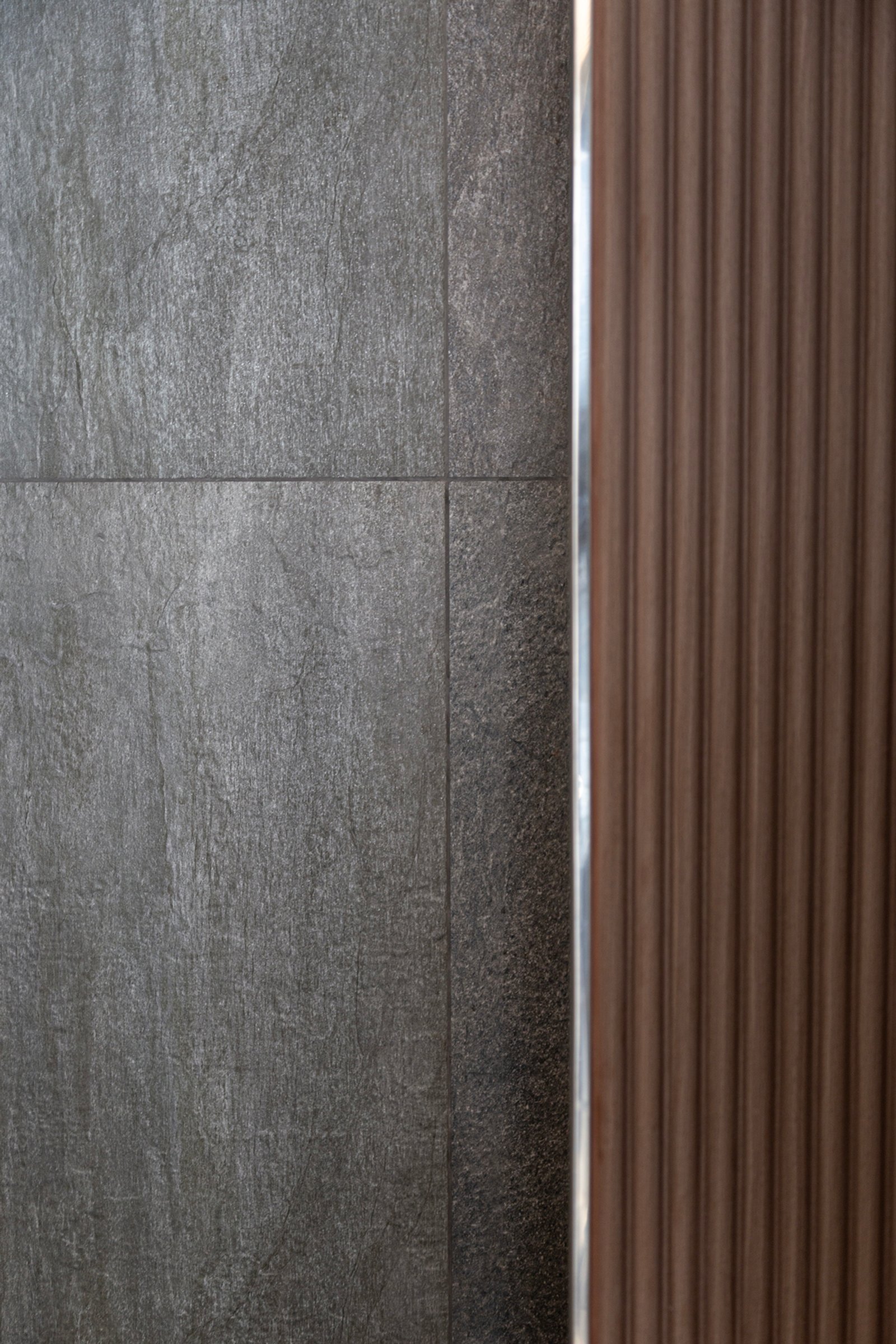 Detalle de pared con baldosas de piedra gris y listones de madera oscura — proyecto Proyecto Gaby P. , por LINEA NETA diseño interior , en Canning