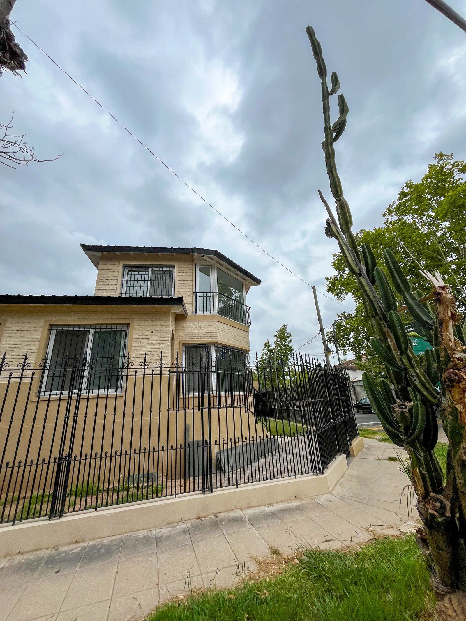 fachada de casa com cactos altos e portão de ferro — projeto Instalación de Radiadores en Tigre, por Climatizacion HD, em B1648 Tigre