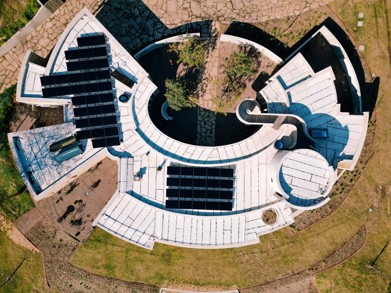 moderno edificio comercial curvo con paneles solares — proyecto Pueblo Mío, en Maldonado
