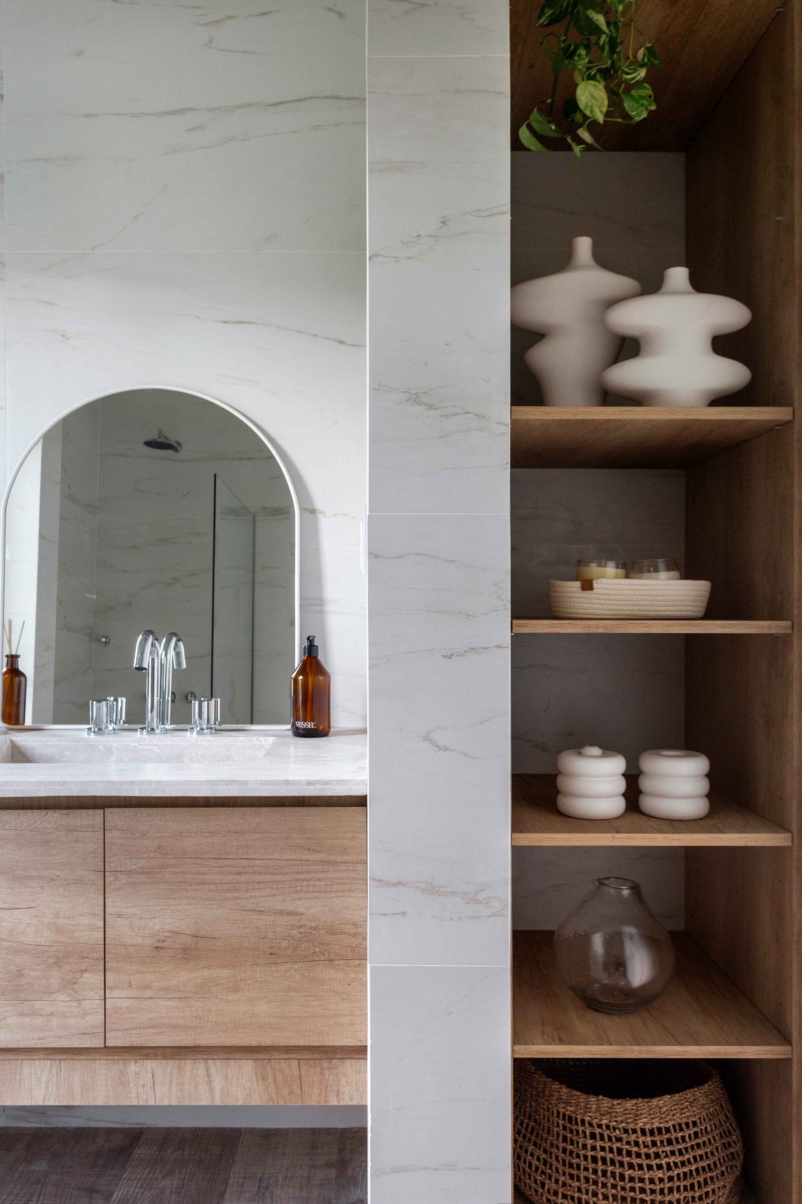 Baño moderno con espejo curvo y estantes de madera — proyecto Santa Ines II, por Estudio Stepa, en Ezeiza