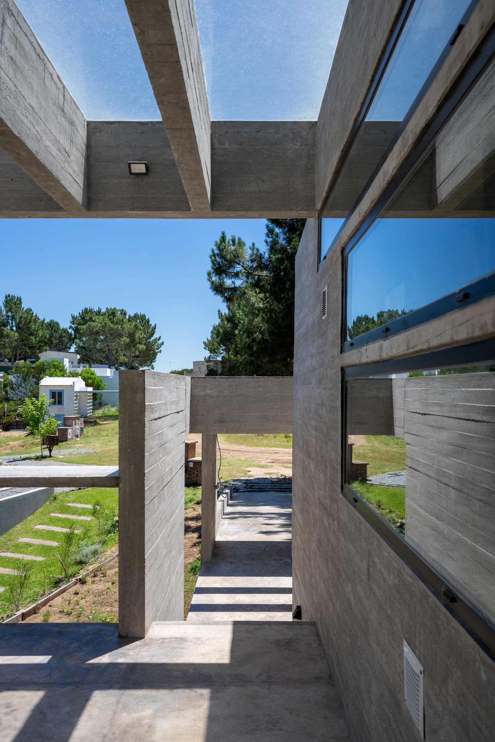 Fachada de concreto aparente com claraboia e amplas janelas — projeto Casa Senderos, por Besonías Almeida arquitectos, em X6VF+67