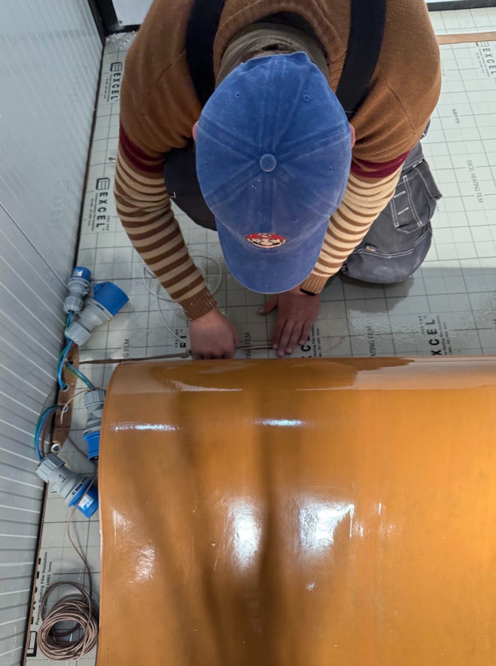 persona instalando material naranja en piso de obra — proyecto Casa Modular, por HEAT LIFE, en Buenos Aires