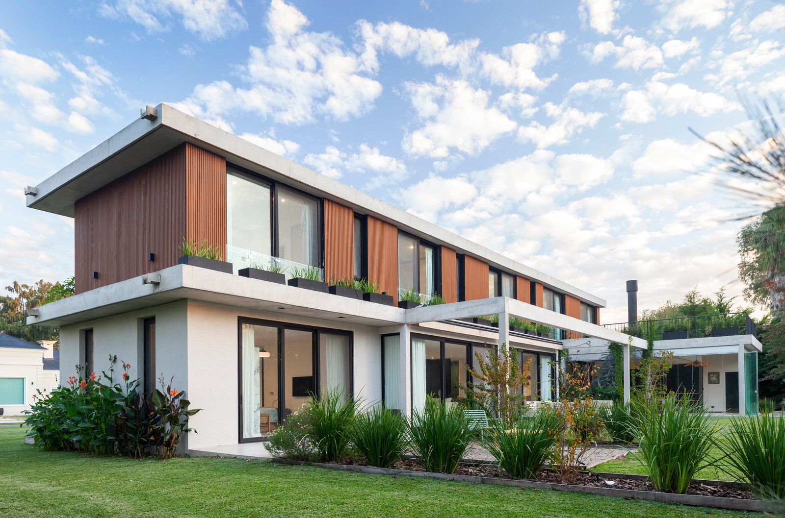 Fachada moderna con amplios ventanales y detalles en madera — proyecto CASA HS143, por A'PRIMA - Arquitectura Sustentable, en km 7.5 Ruta 25