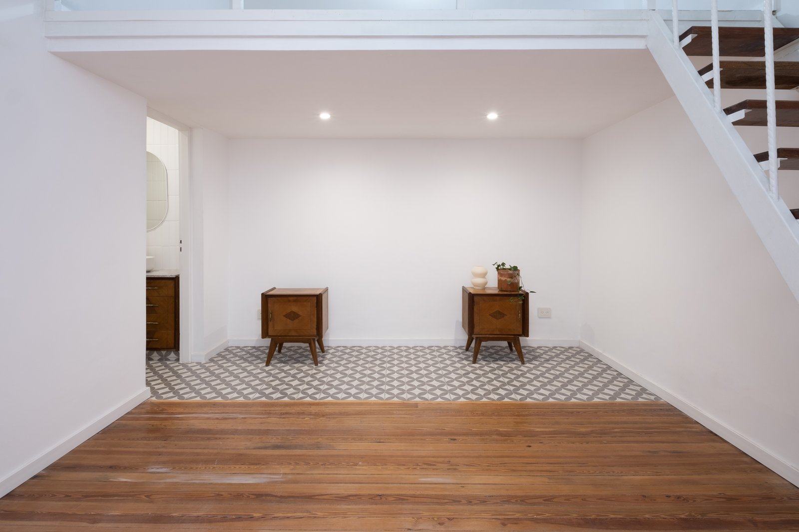 Espaço interno vazio com escada flutuante e piso de madeira e azulejo — projeto Casa Patio, por Herrera Ungaro, em San Cristóbal