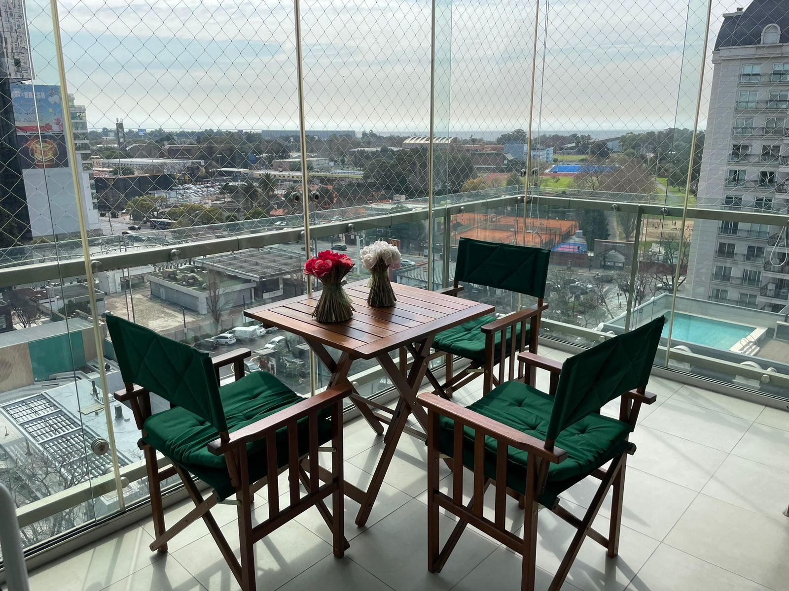 Balcón con vista a la ciudad y muebles verdes — proyecto Balcón y Terraza, por Casa Nuñez