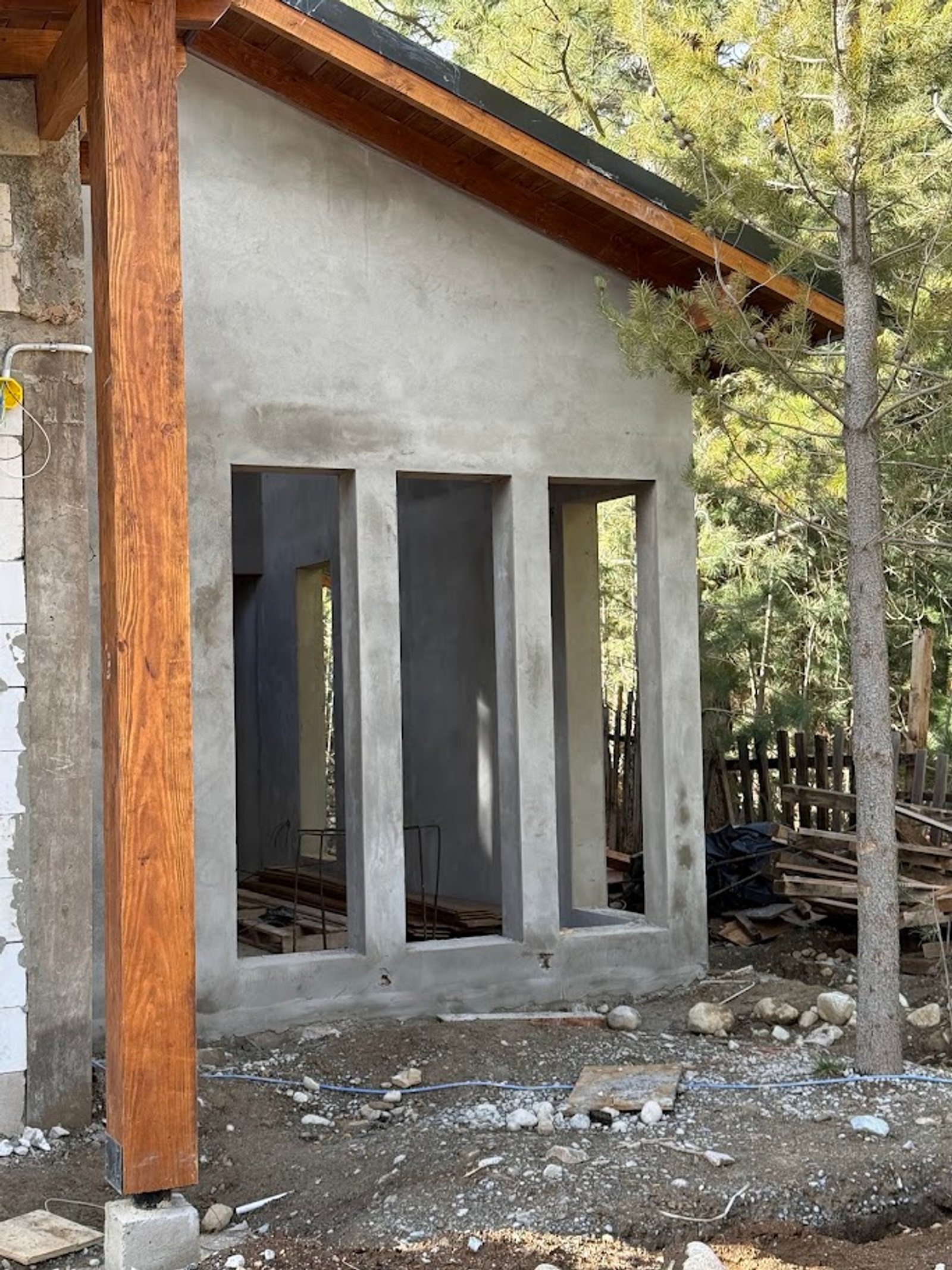 fachada em construção com viga de madeira e concreto aparente — projeto Casa Q11, por Showhouse Bariloche, em San Carlos de Bariloche
