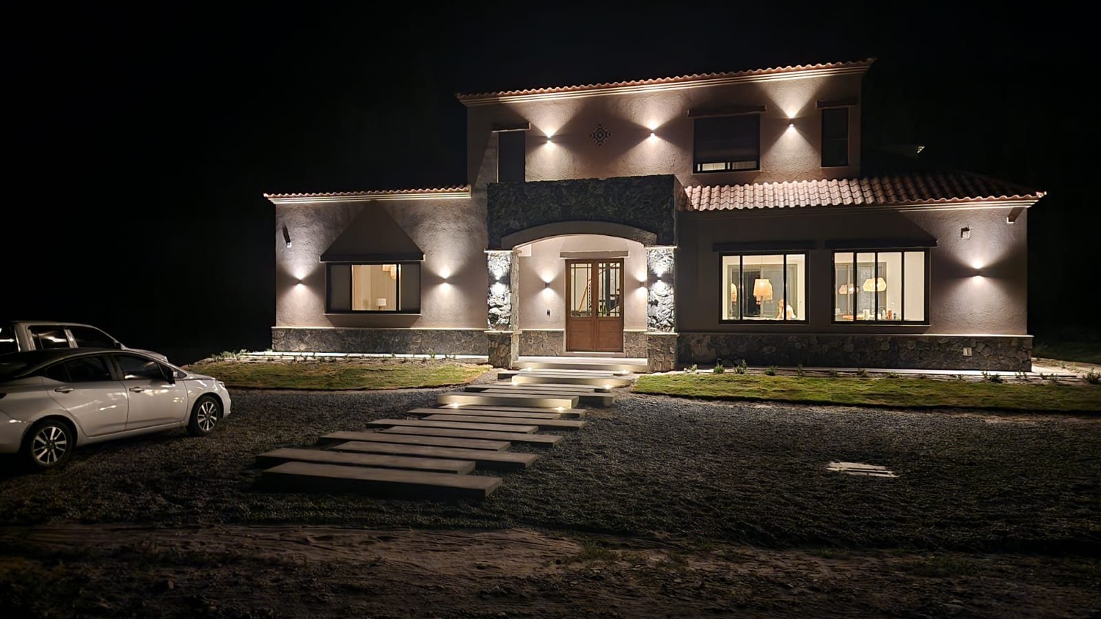 fachada de casa moderna iluminada à noite — projeto Ca La Estancia, por Luciana González Anderson, em Cafayate