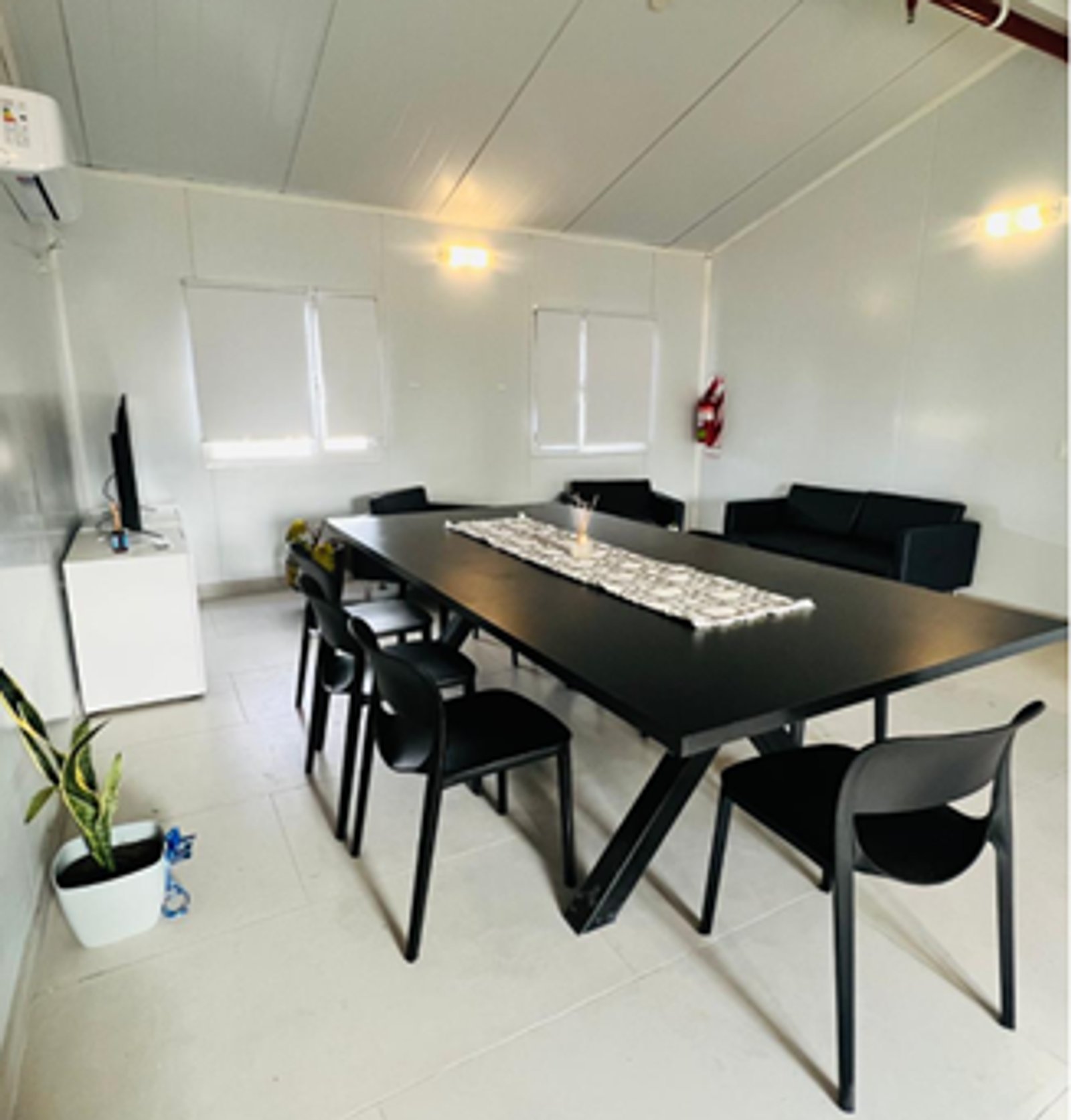 Sala de reuniones moderna con mesa negra y sofás — proyecto OBRAS EN YACIMIENTO CVX, por Arquitecto Germán Müller, en Neuquén