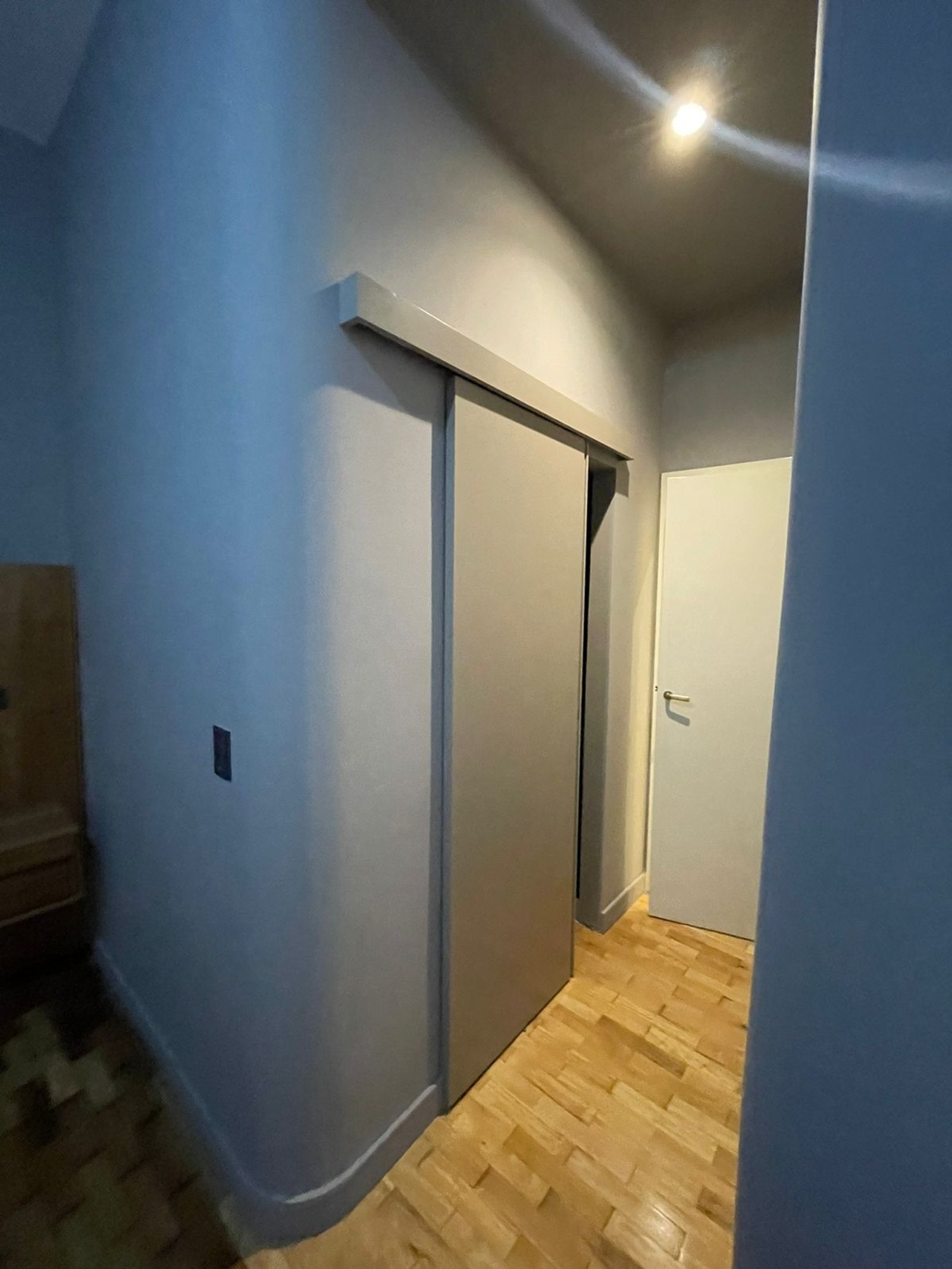 Pasillo moderno con puerta corrediza integrada y suelo de madera — proyecto Uruguay y Juncal , por Estudio Babilonia , en Buenos Aires