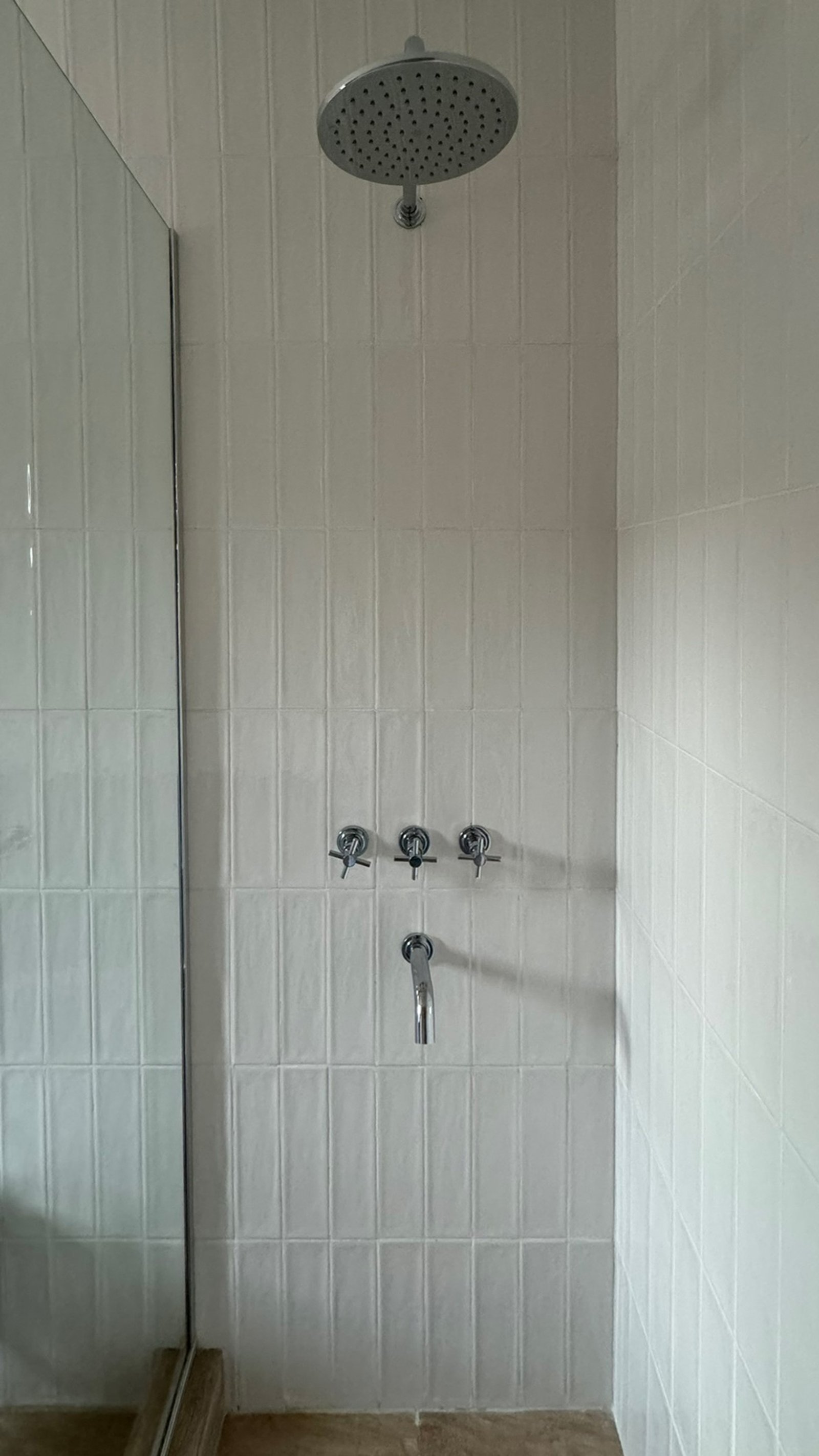 Banheiro moderno com azulejos verticais brancos e torneira cromada — projeto Casa MC, por Hermann Arquitectos, em Bv. Central