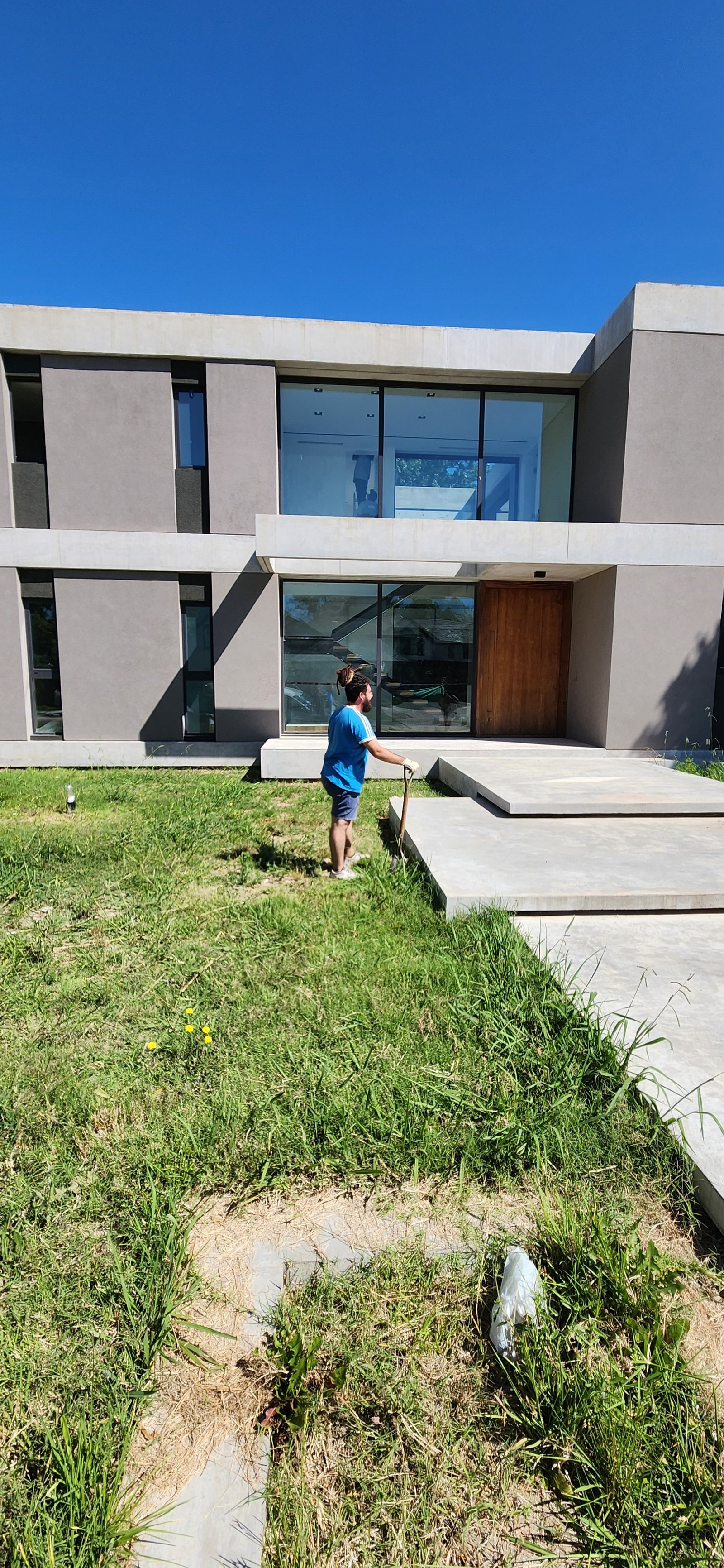 fachada moderna com jardim e homem trabalhando — projeto Casa CAD, por Estudio Rifahi, em Moreno