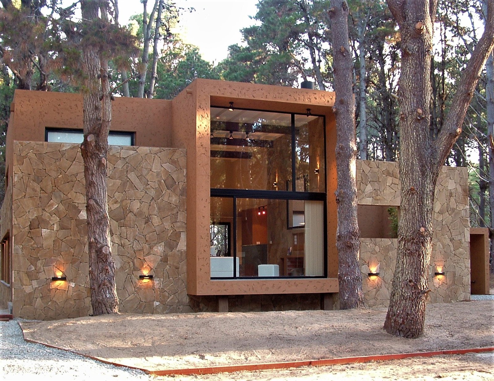 Fachada moderna con piedra y vidrio en bosque — proyecto LA  ALHAMBRA, por GJF estudio, en Costa del Este