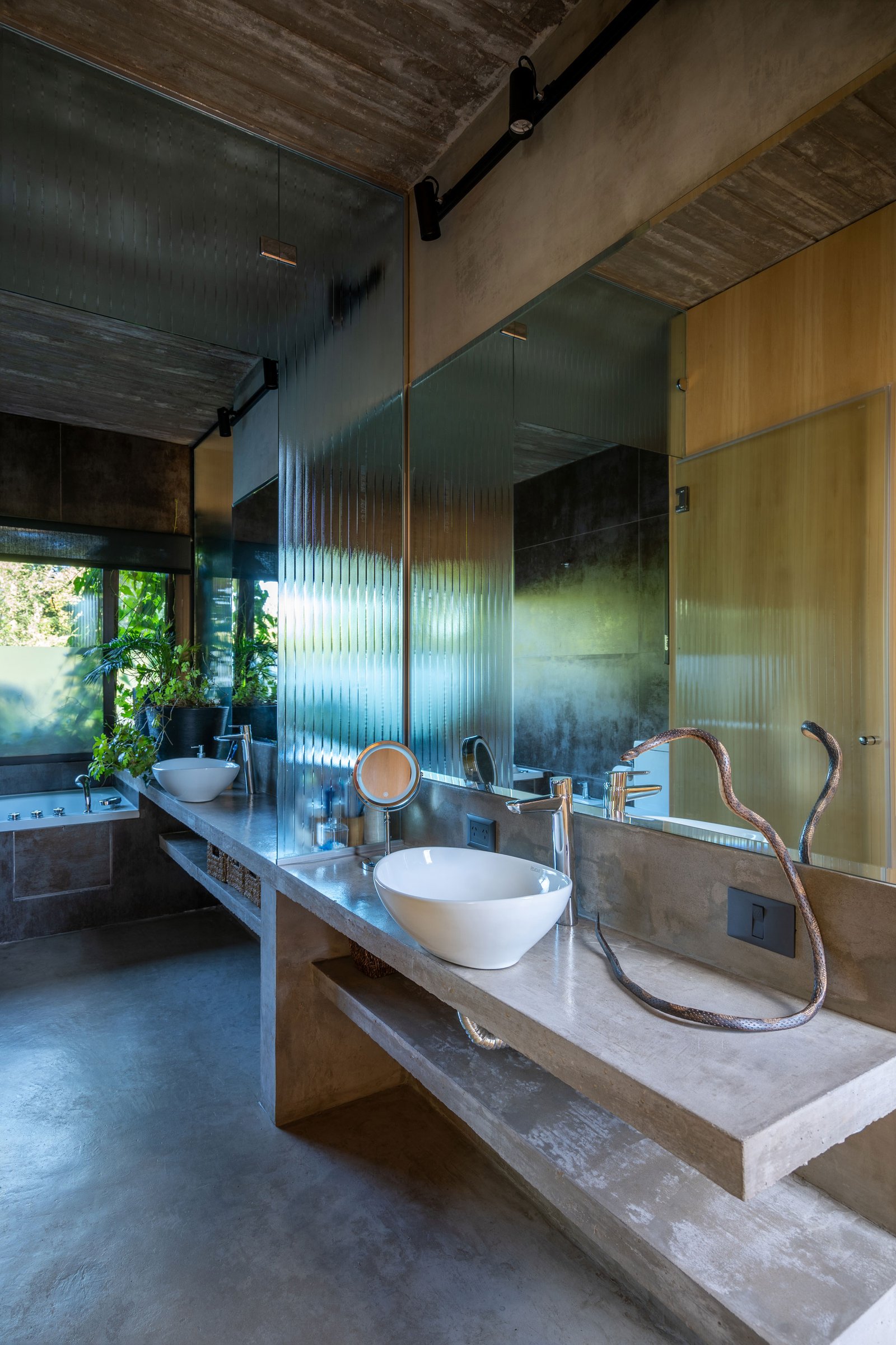 Baño industrial moderno con concreto y vidrio acanalado — proyecto Casa Leloir, por Besonías Almeida arquitectos, en Parque Leloir