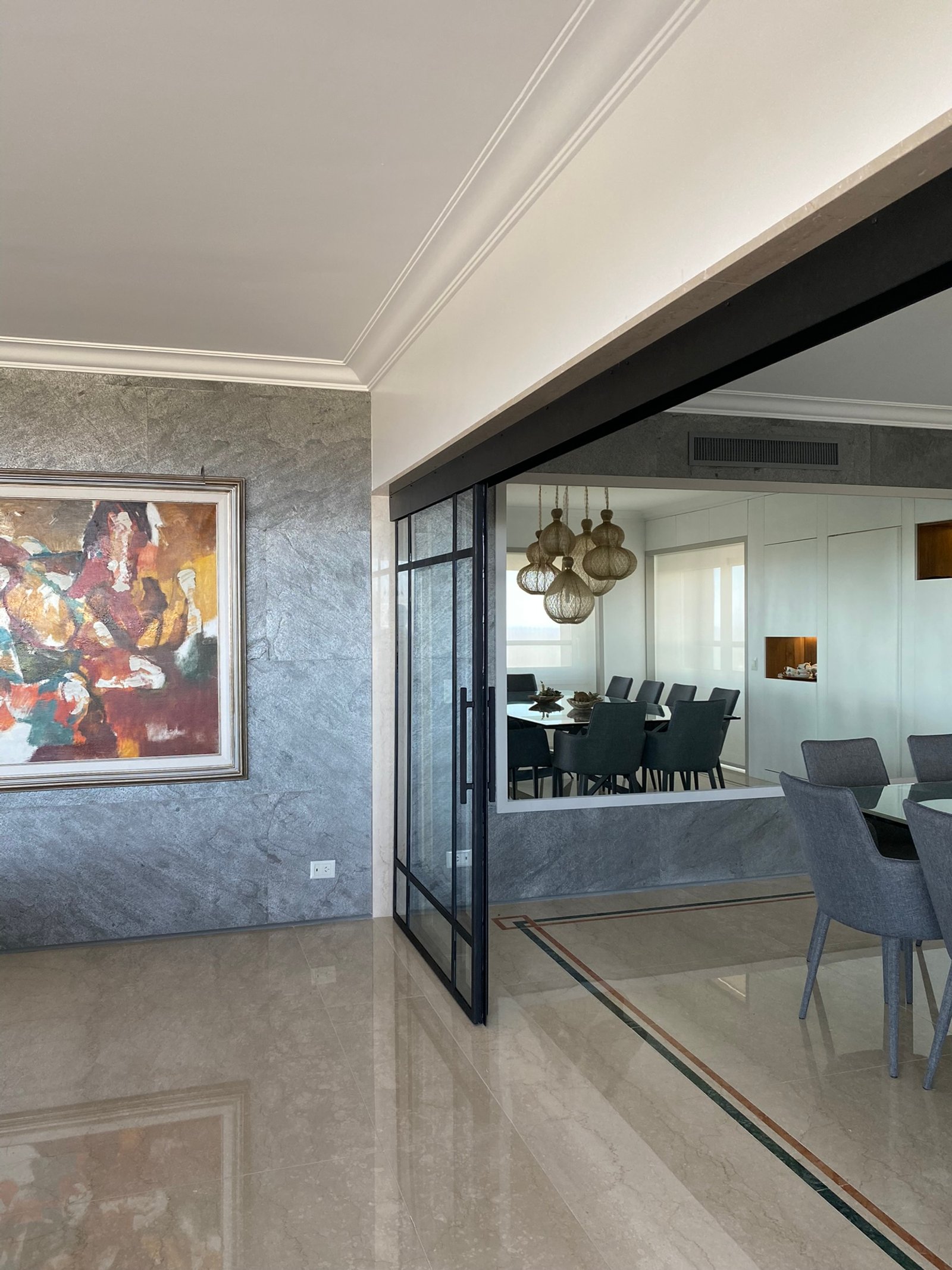 Comedor moderno con pared de piedra texturizada y puerta de vidrio — proyecto Libertador I, por MDBK Arquitectura, en Palermo