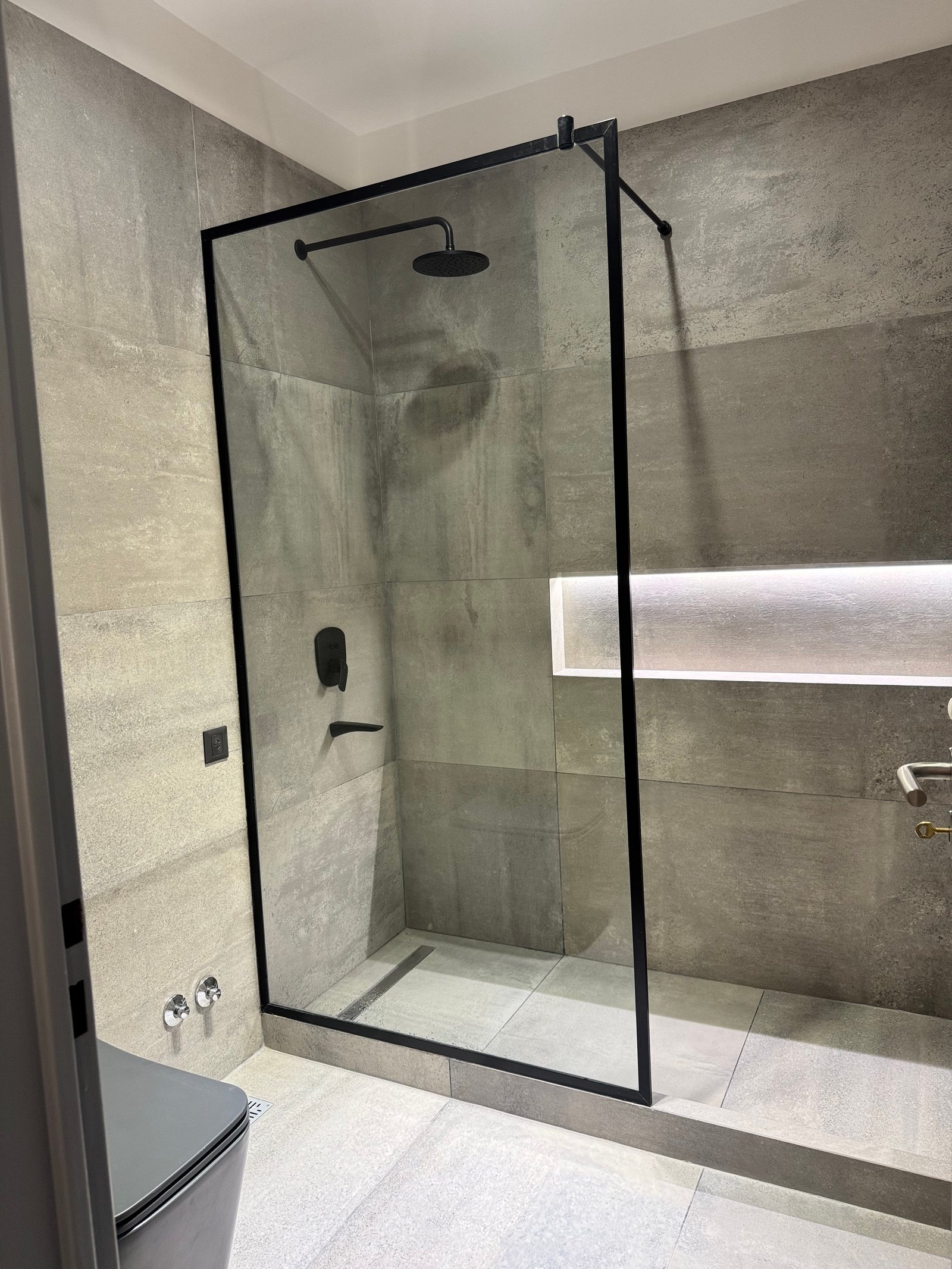 Baño moderno con ducha de vidrio y azulejos grises — proyecto italia 2, por Estudio Grupo 32, en Vicente López