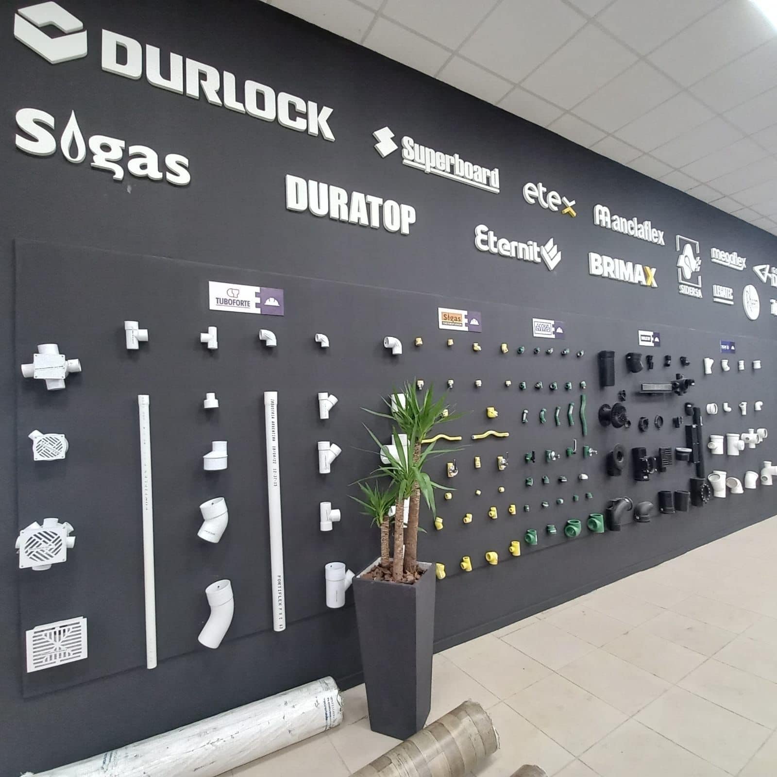 Local de venta de materiales de plomería, con exhibidores blancos en pared negra — proyecto Edify Posadas, por Arquitecto Gustavo Maidana, en Posadas