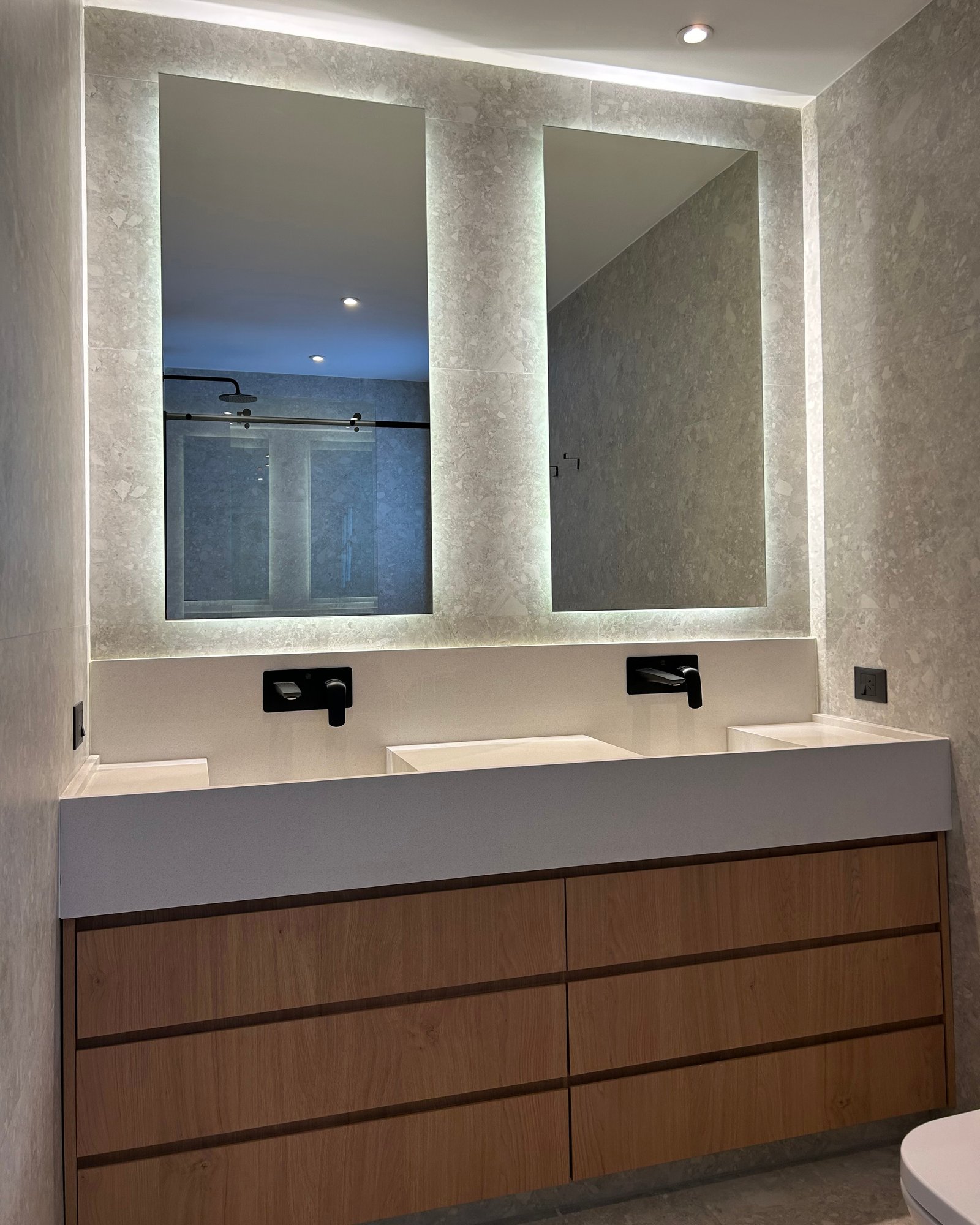 Baño moderno con doble lavabo, espejos retroiluminados y mueble de madera — proyecto LIBERTADOR II, por ESTUDIO TEZ, en Palermo