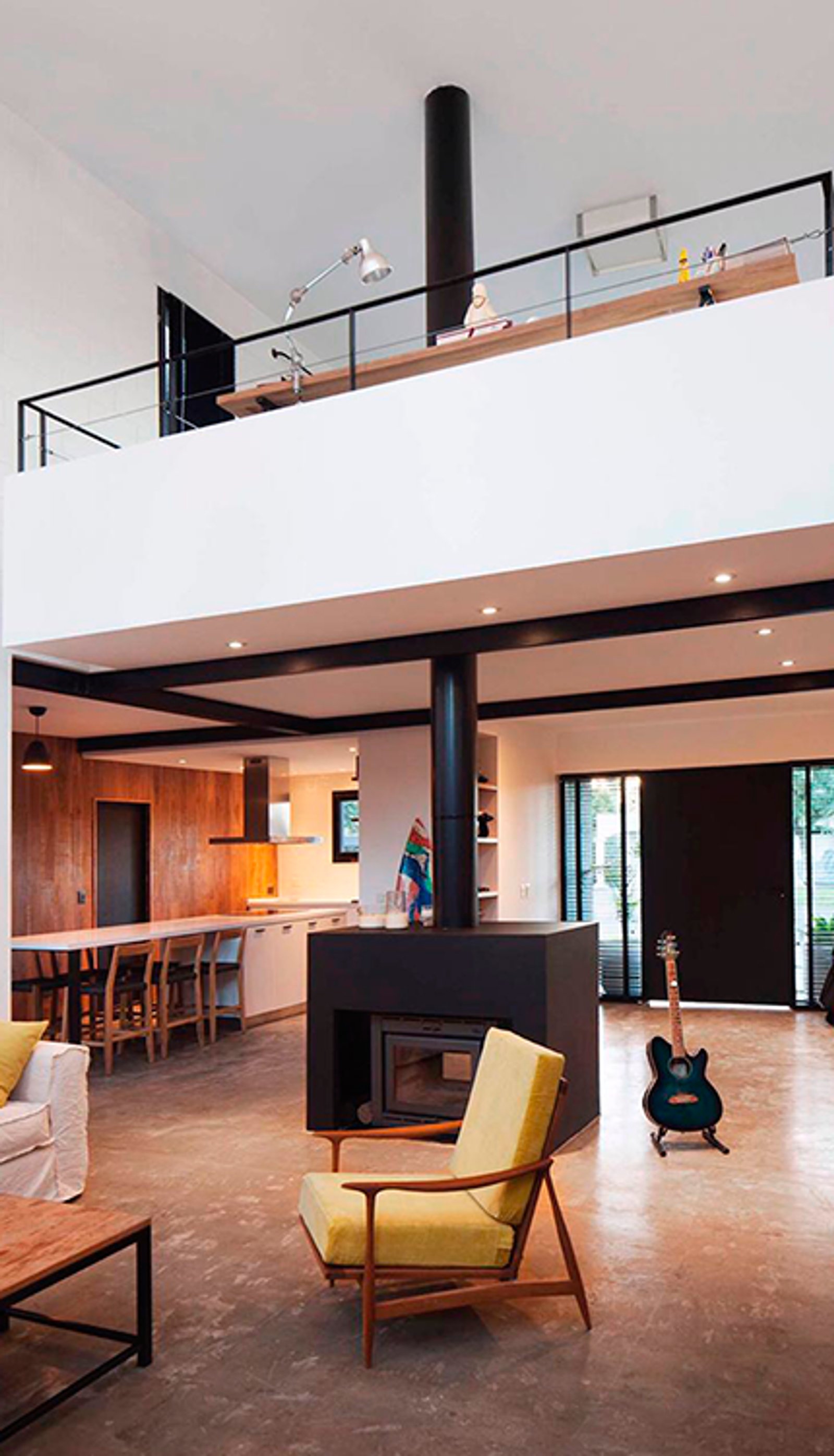 Sala moderna industrial com pé-direito duplo, lareira e poltrona amarela — projeto Casa coco, por Estudio PK, em B1648 Tigre
