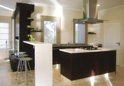 Cocina moderna con isla negra, mesada blanca y piso de madera — proyecto Santa Fe Style, por Ciba Arquitectura