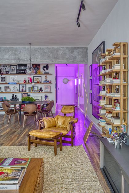 Living moderno con sillón dorado, estantería de madera y puerta fucsia neón — proyecto Hugo Gloss, por Studio Ro-ca