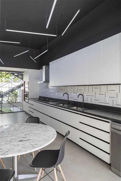 Cocina minimalista blanca con mesada negra e iluminación lineal — proyecto Casa 636, por Coda Arquitetos