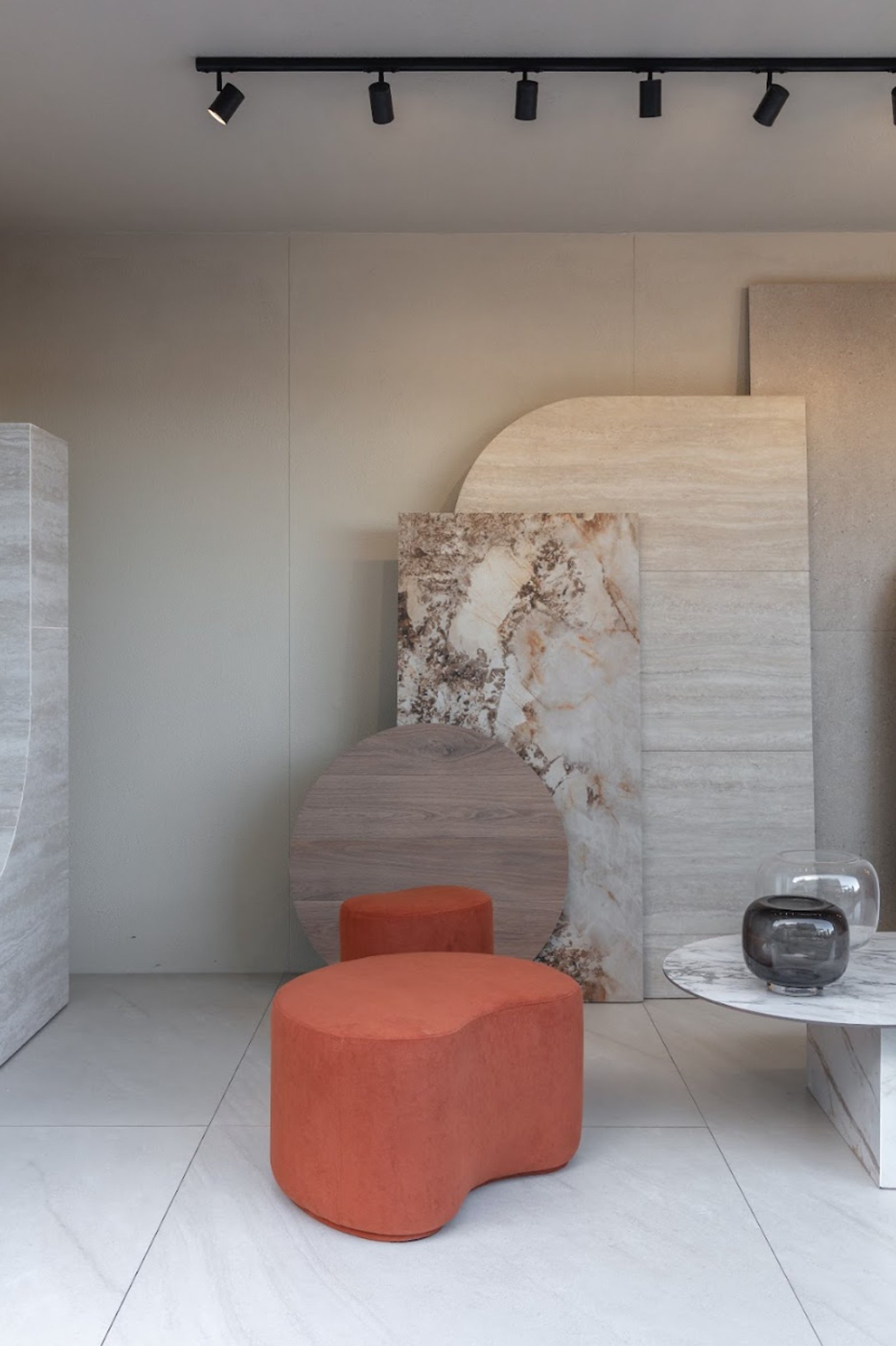 espacio moderno con poufs terracota y exhibición de piedra — proyecto Experiencia Living 2026, por San Lorenzo Design, en Cam. de los Remeros 1585