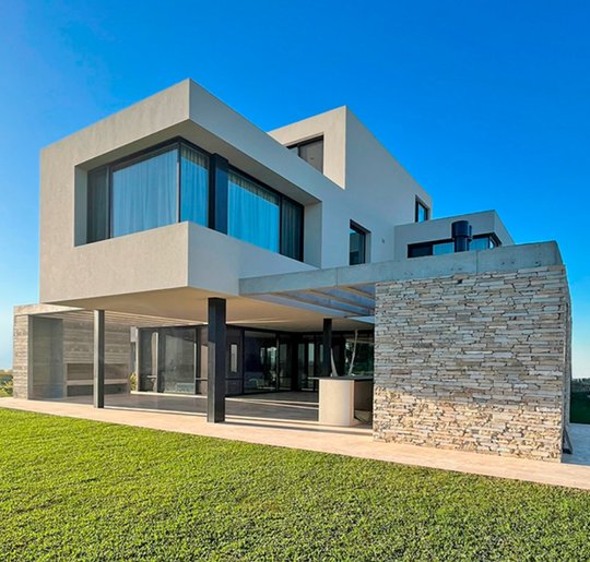 fachada moderna de casa con voladizos y muro de piedra — proyecto Casa EM10, por Aluar División Elaborados