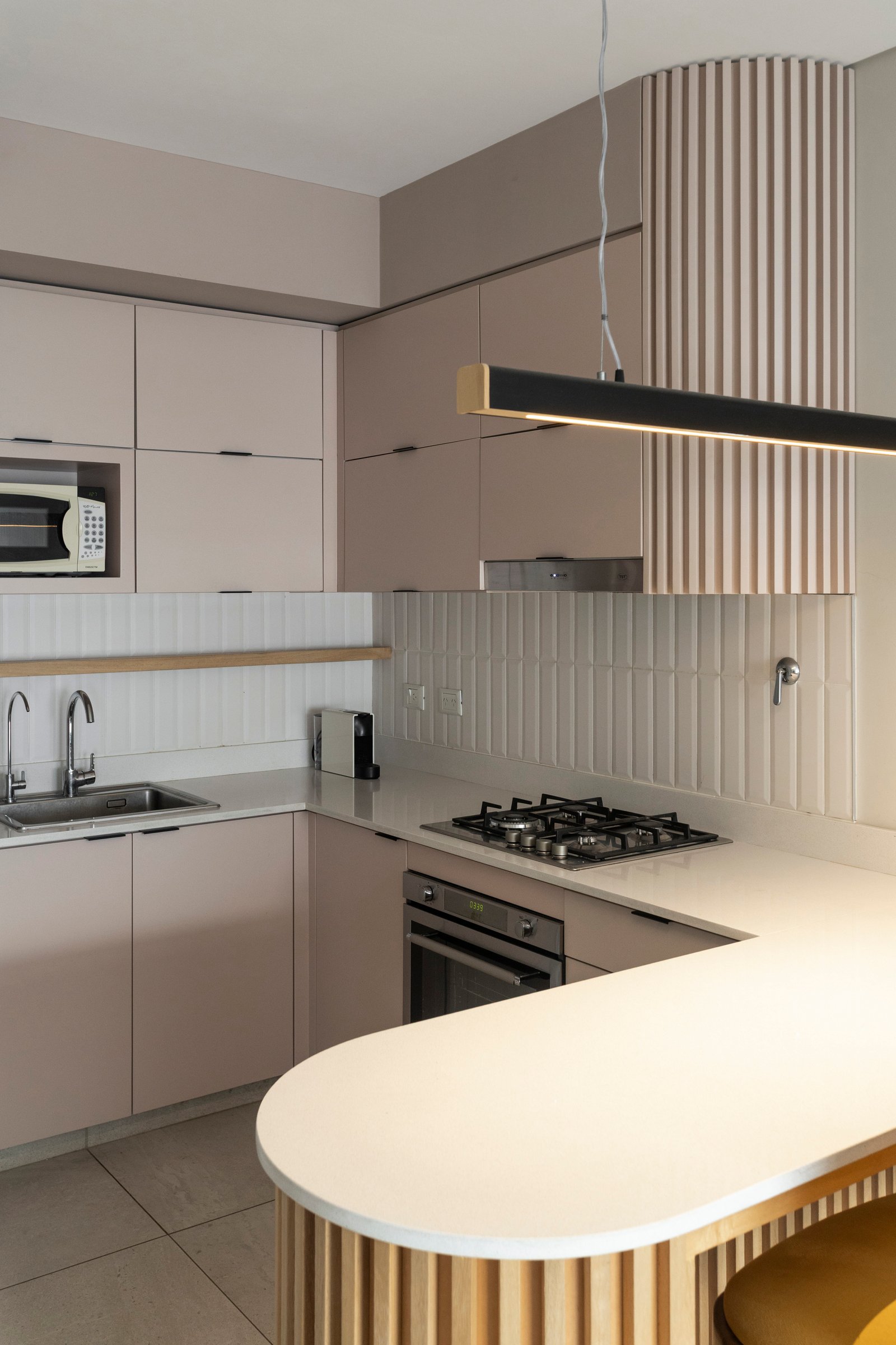 Cocina moderna con isla curva y revestimientos de madera — proyecto ARGERICH, por La Nave Arq., en Villa Pueyrredón