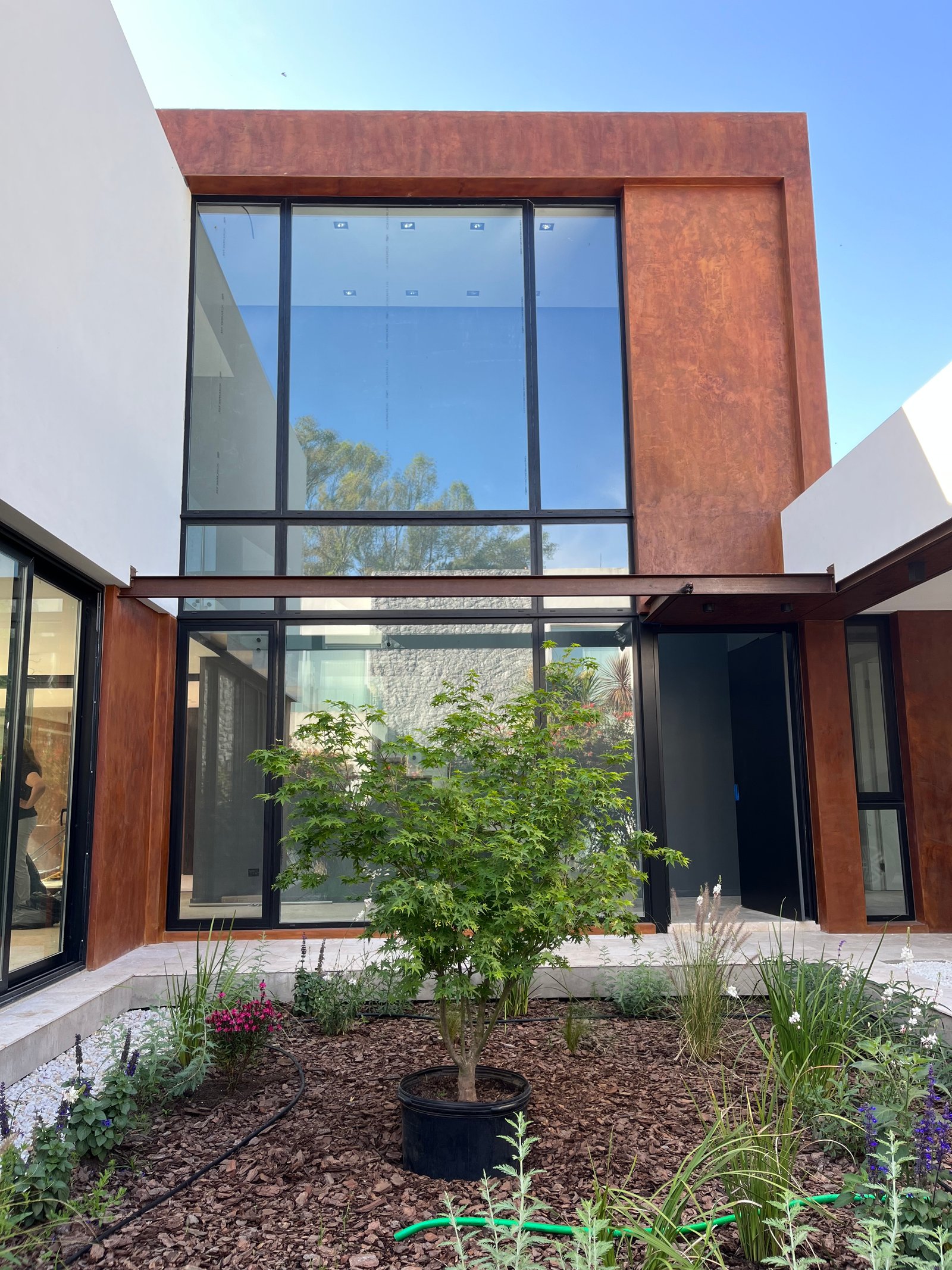 Fachada de casa moderna con grandes ventanales y detalles en óxido — proyecto Casa La Reserva , por Marianela Grosso, en Ruta Panamericana No. 9 Km 61